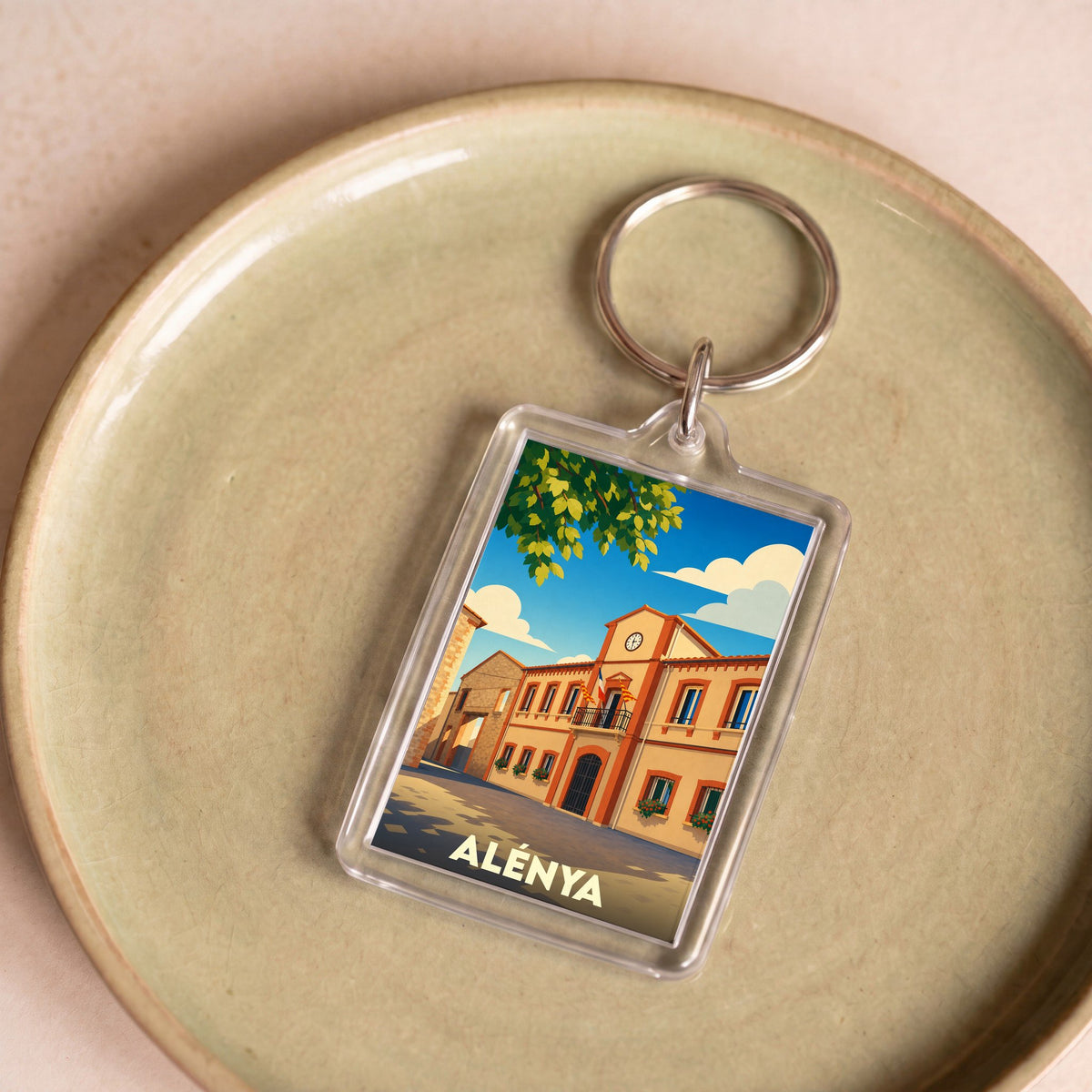 Porte-clés souvenir de la ville d'Alénya avec une illustration stylisée de sa mairie.