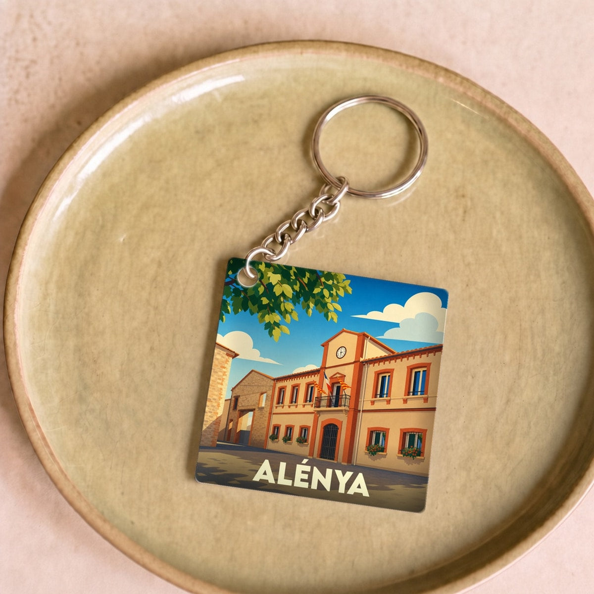 Porte-clés souvenir de la ville d'Alénya avec une illustration stylisée de sa mairie.