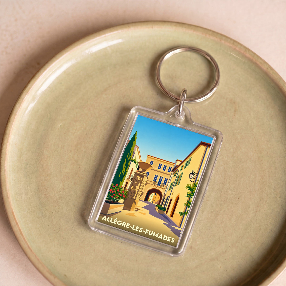Porte-clés souvenir de la ville d'Allègre-les-Fumades avec une illustration stylisée.