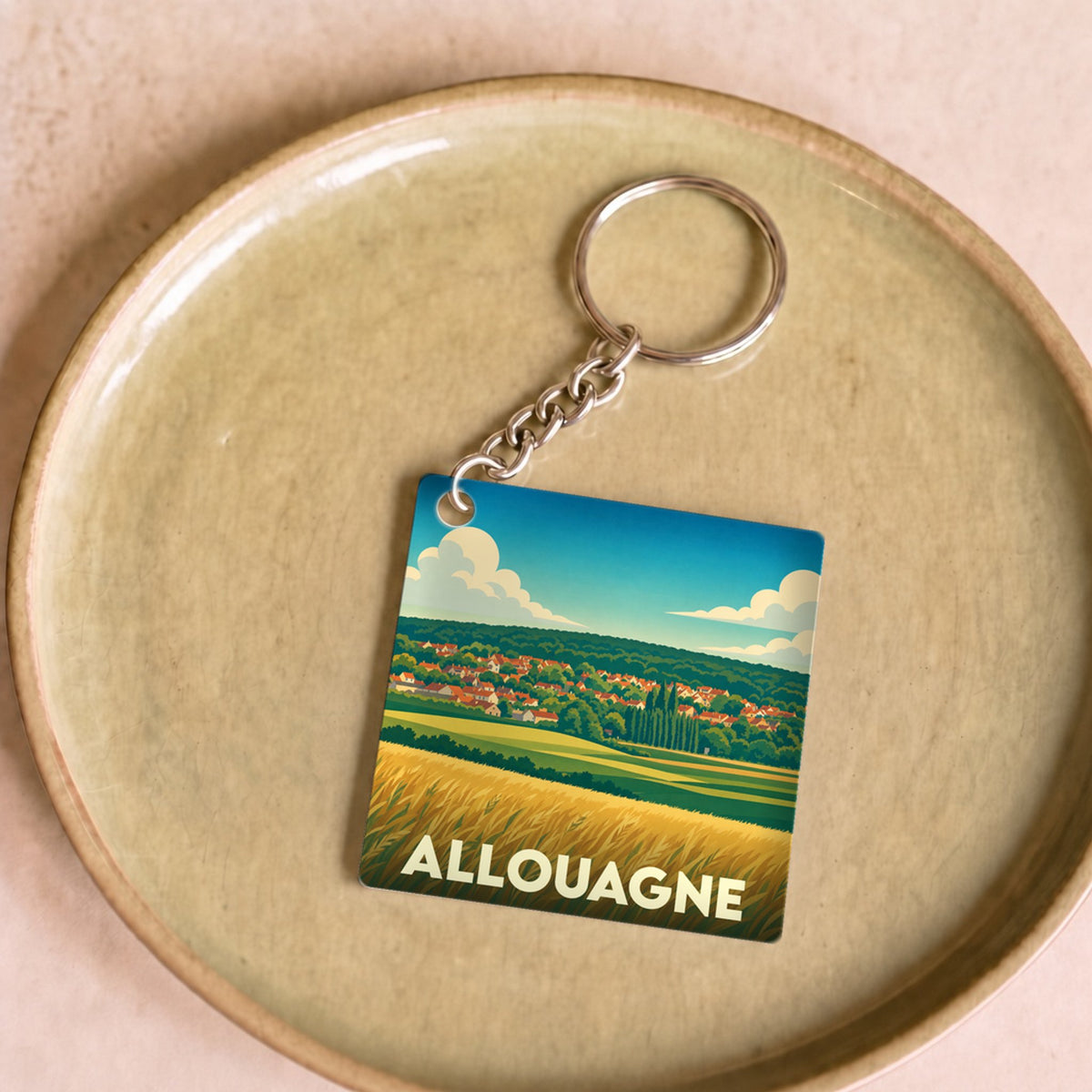 Porte-clés souvenir de la ville d'Allouagne avec une illustration stylisée de paysages champêtres.