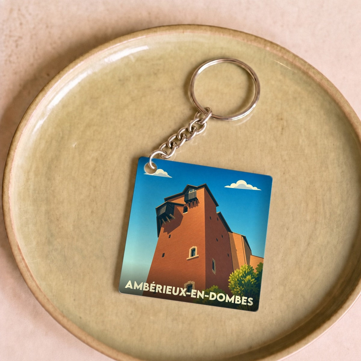 Porte-clés souvenir de la ville de Ambérieux-en-Dombes avec une illustration stylisée de son château.