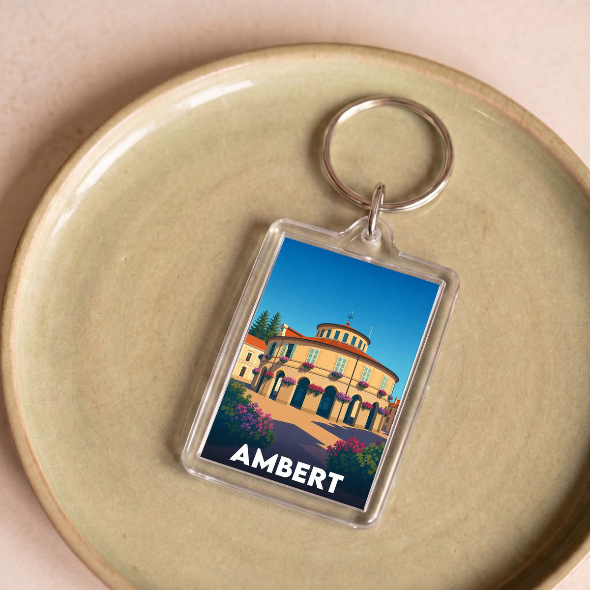 Porte-clés souvenir de la ville d'Ambert avec une illustration stylisée de son hôtel de ville circulaire.