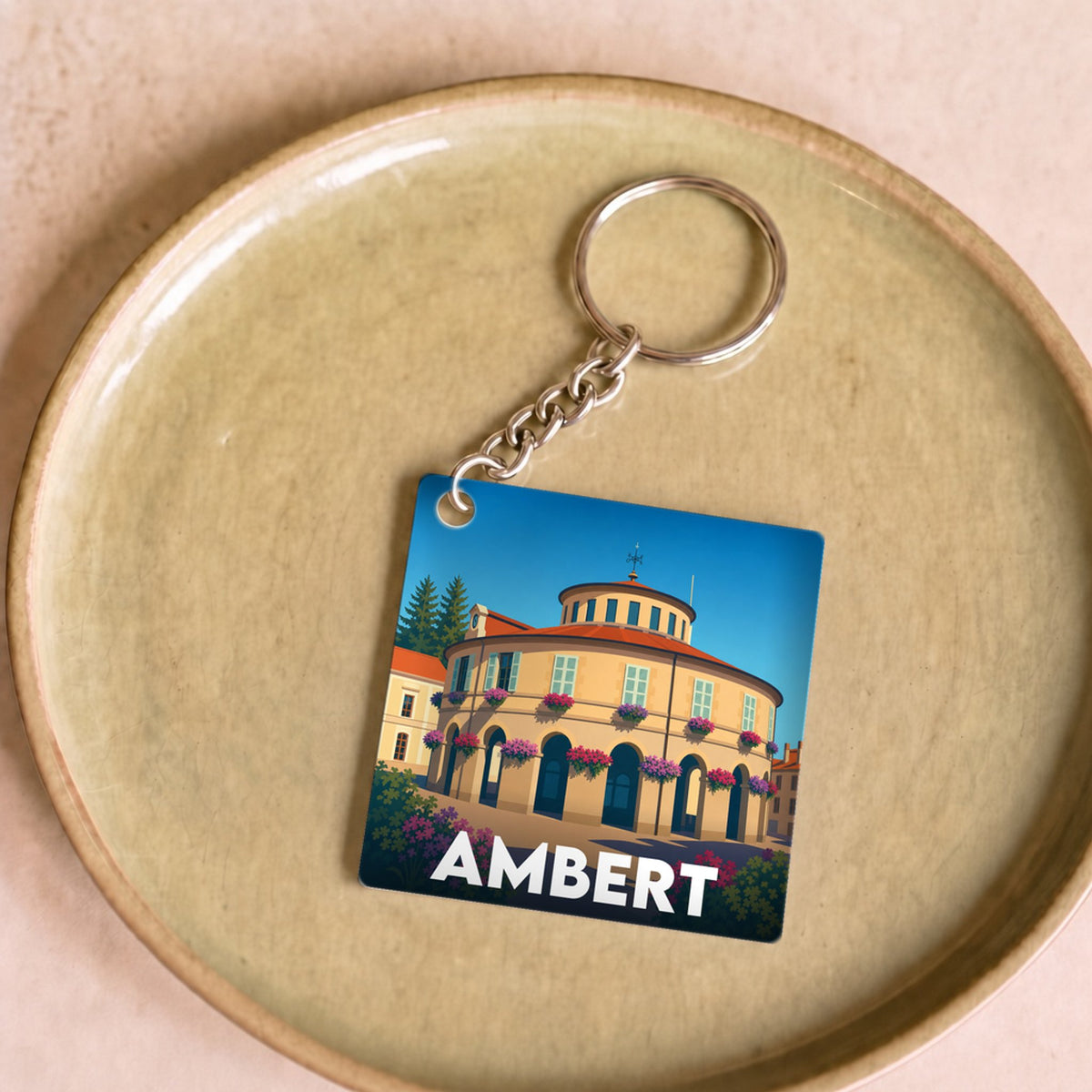 Porte-clés souvenir de la ville d'Ambert avec une illustration stylisée de son hôtel de ville circulaire.