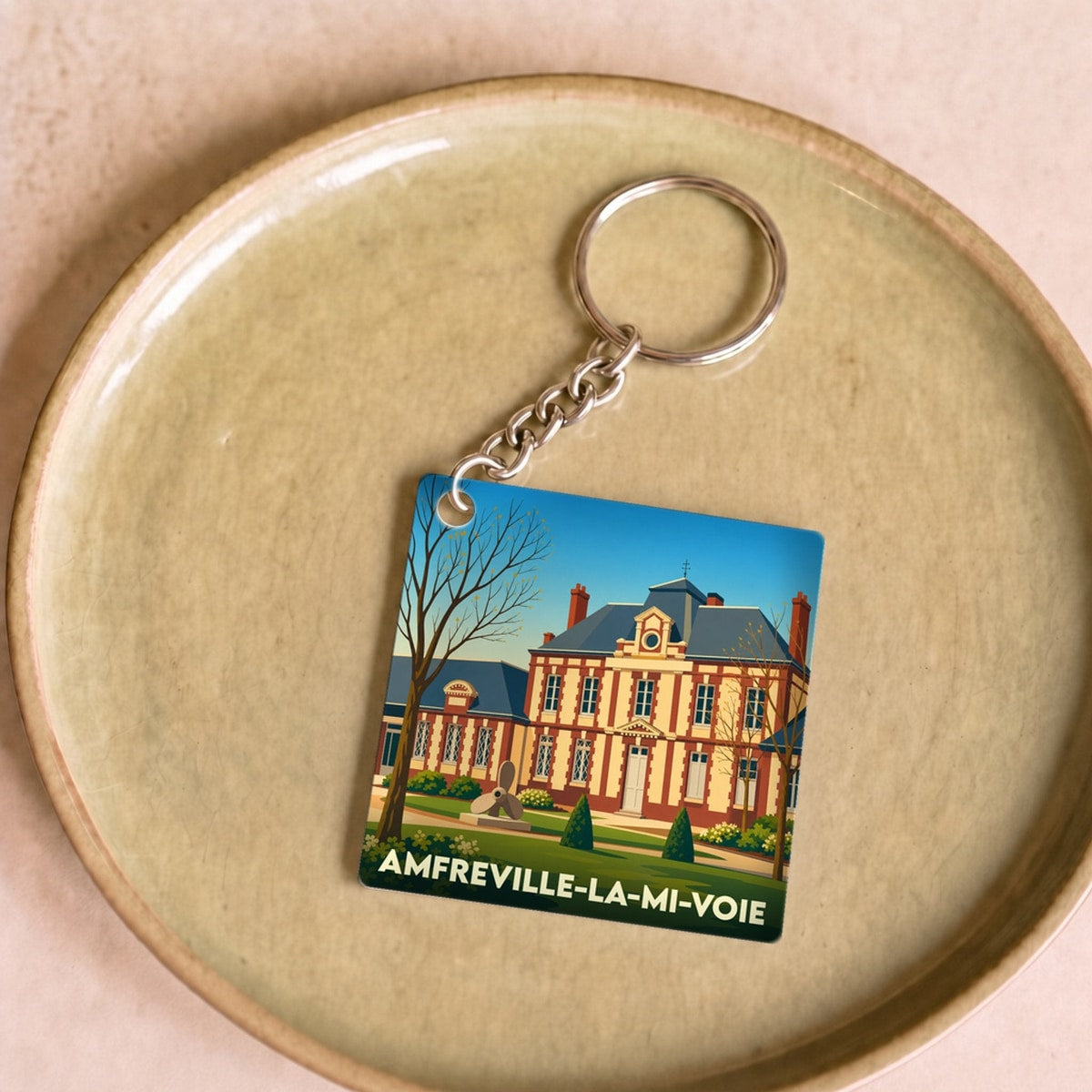 Porte-clés souvenir de la ville d'Amfreville-la-Mi-Voie avec une illustration stylisée de son hôtel de ville.