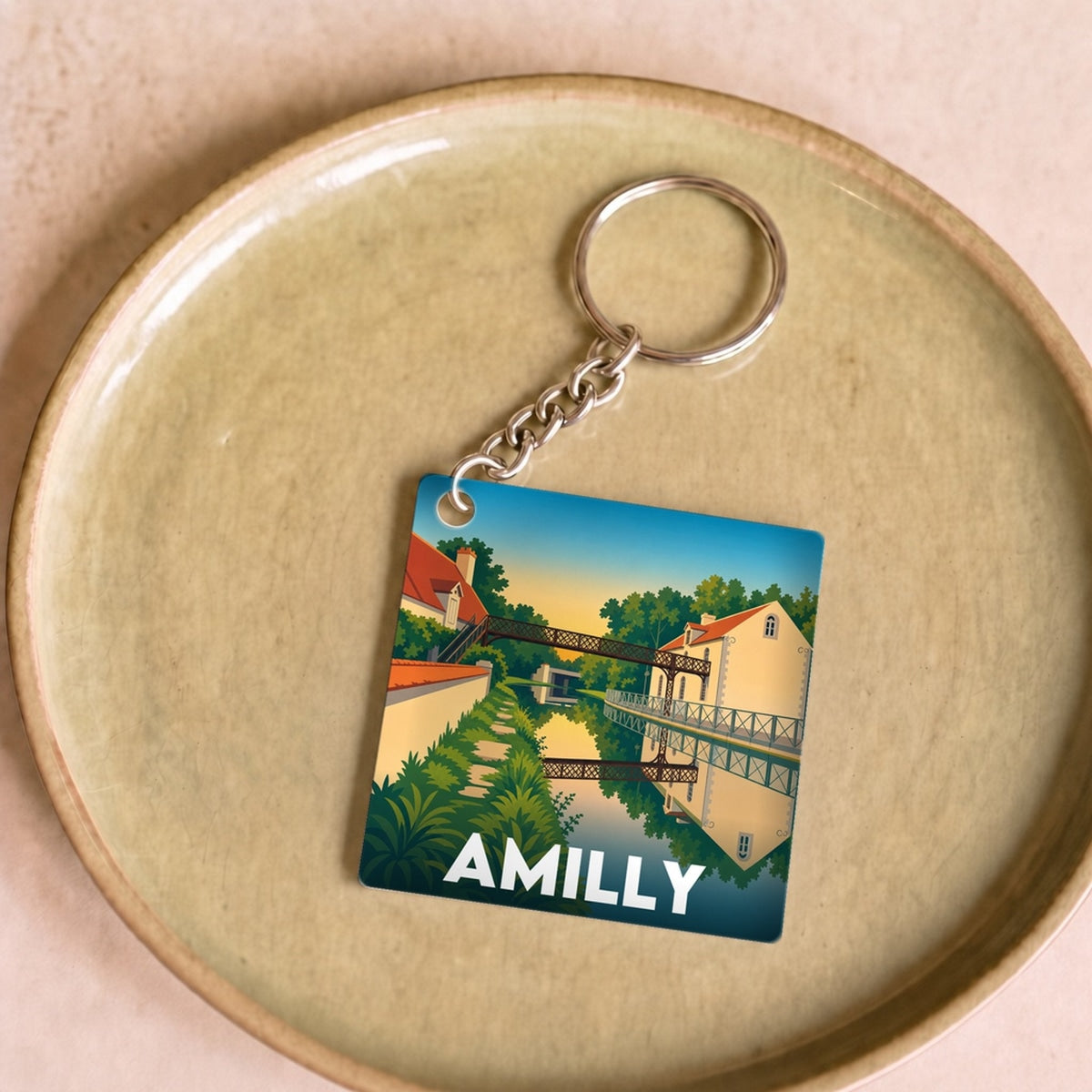 Porte-clés souvenir de la ville d'Amilly avec une illustration stylisée d'un paysage.