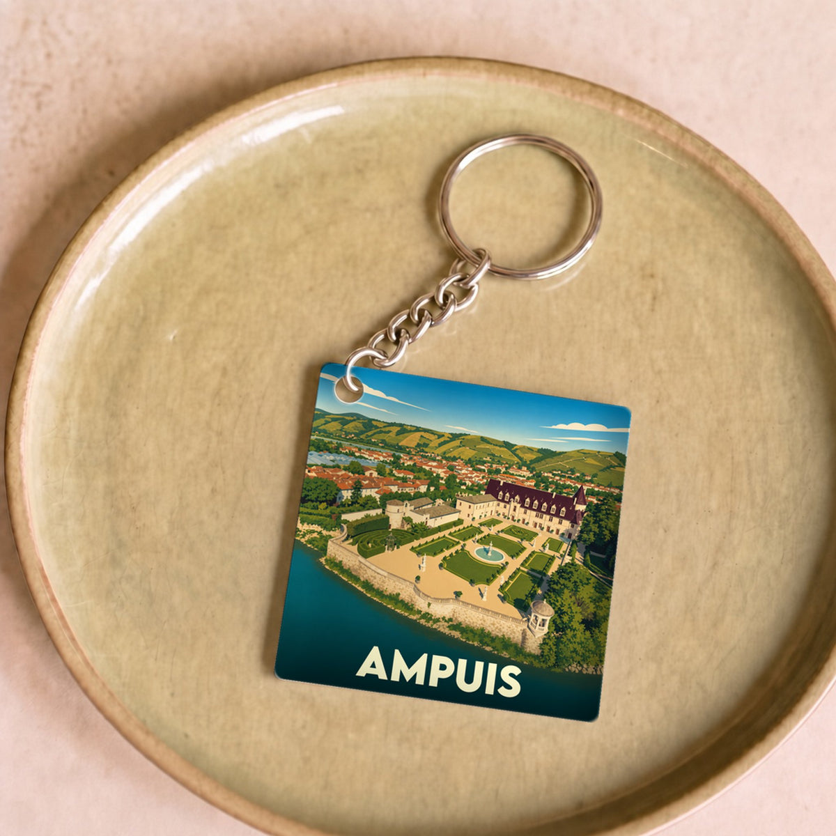 Porte-clés souvenir de la ville d'Ampuis avec une illustration stylisée de son château au bord de l'eau.