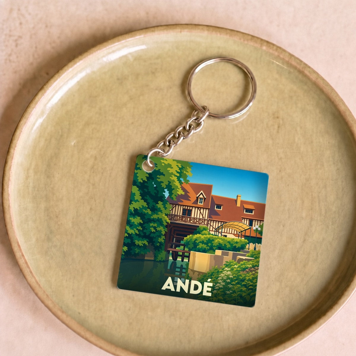 Porte-clés souvenir de la ville de Andé avec une illustration stylisée.