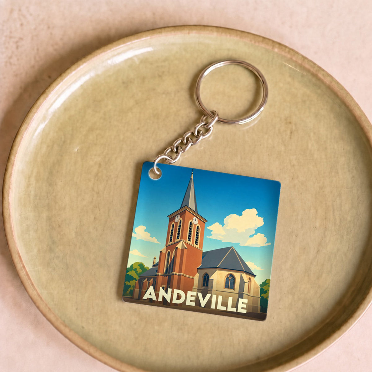 Porte-clés souvenir de la ville d'Andeville avec une illustration stylisée de son église.
