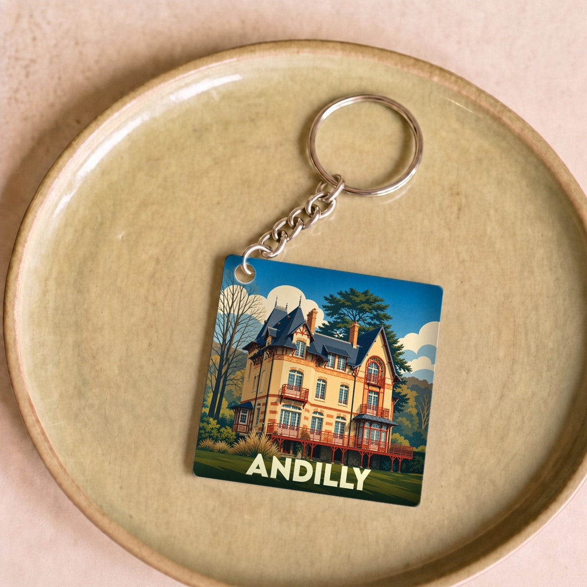 Porte-clés souvenir de la ville d'Andilly avec une illustration stylisée d'une demeure historique.