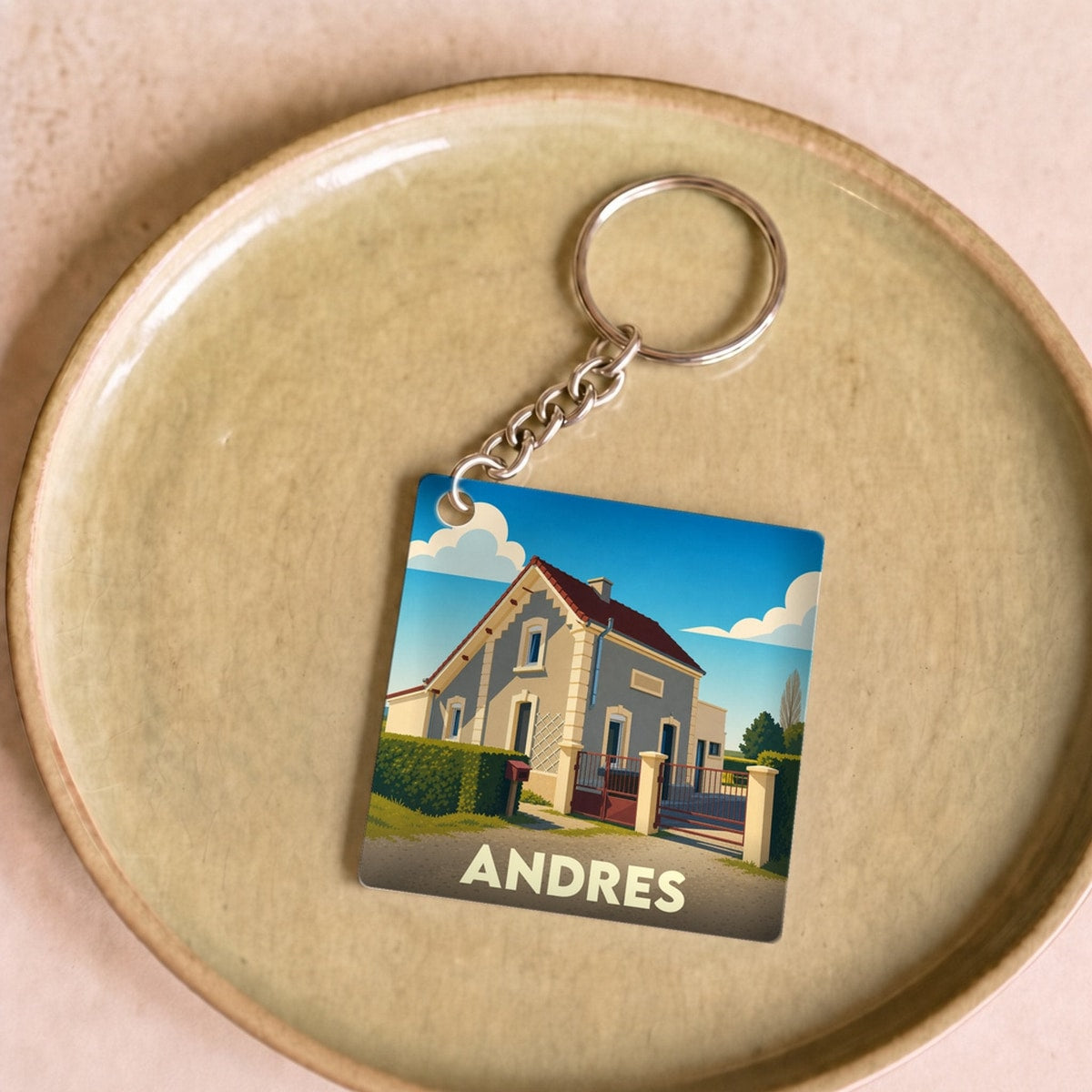Porte-clés souvenir de la ville de Andres avec une illustration stylisée d'une maison locale.