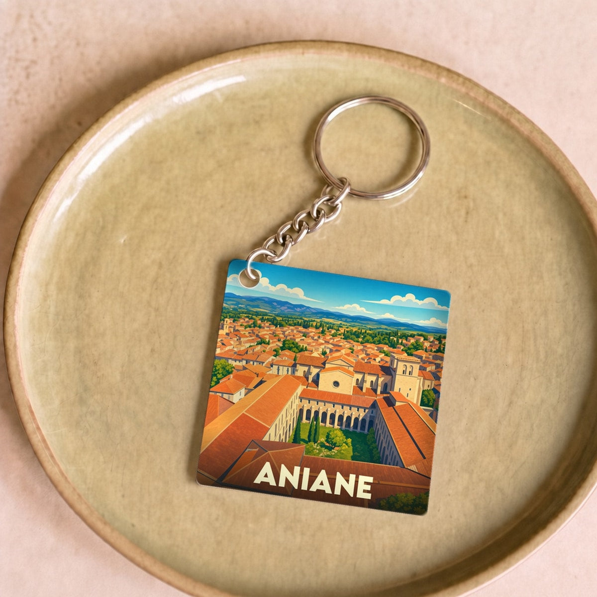 Porte-clés souvenir de la ville d'Aniane avec une illustration stylisée.