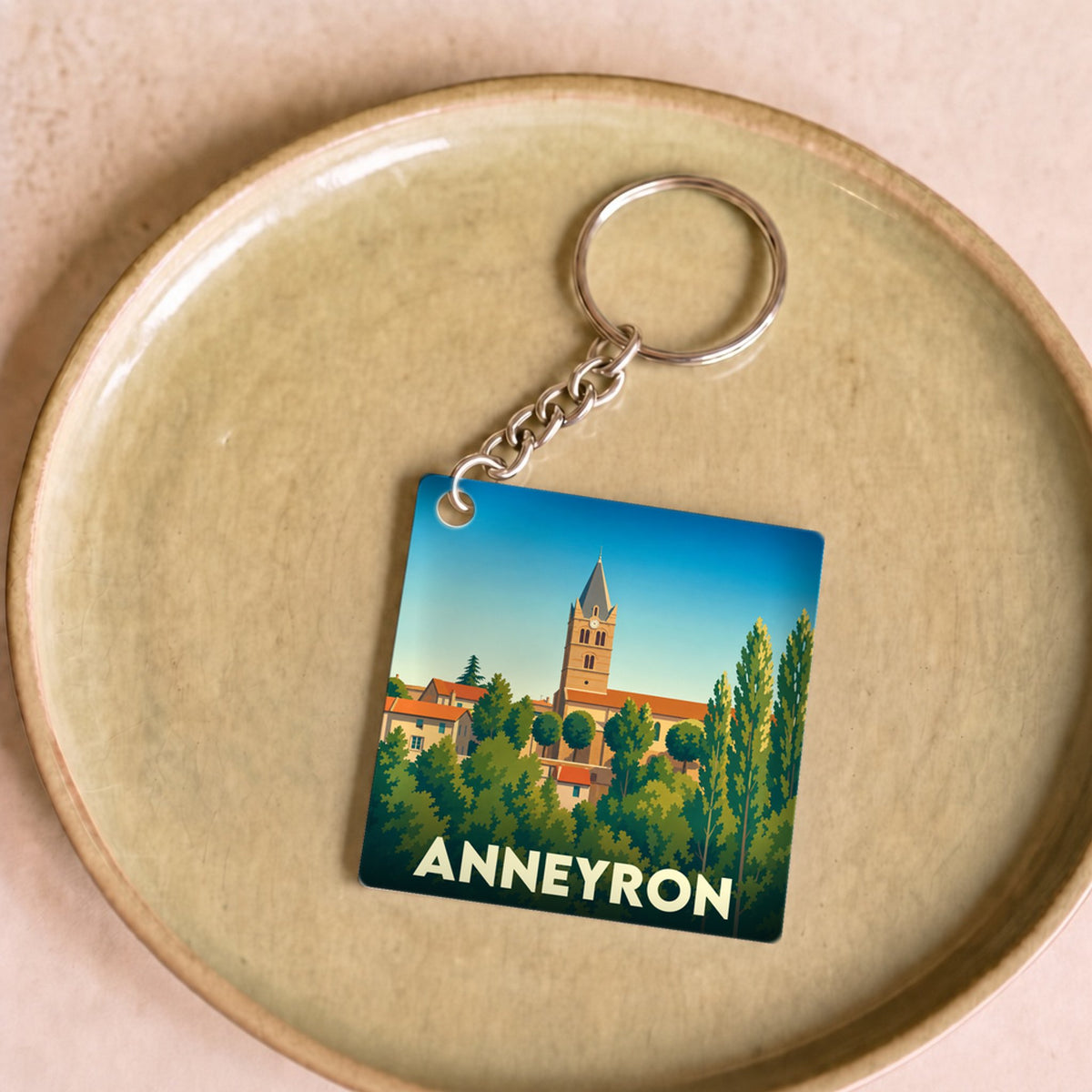 Porte-clés souvenir de la ville d'Anneyron avec une illustration stylisée de son clocher émergeant des arbres.