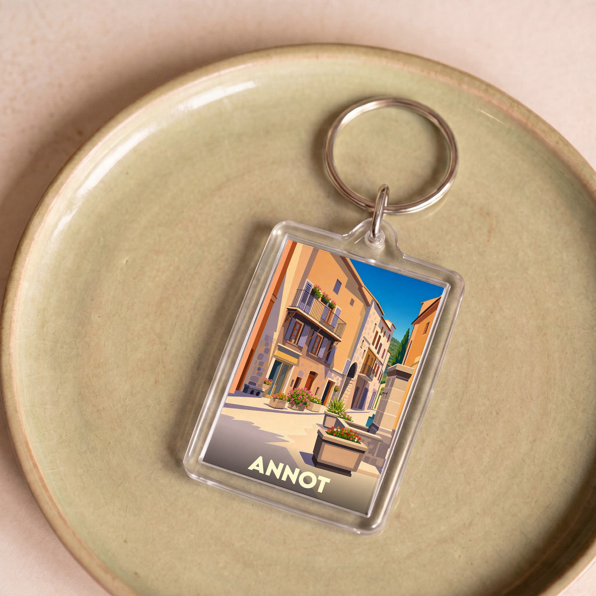 Porte-clés souvenir de la ville d'Annot avec une illustration stylisée d'une ruelle ensoleillée.