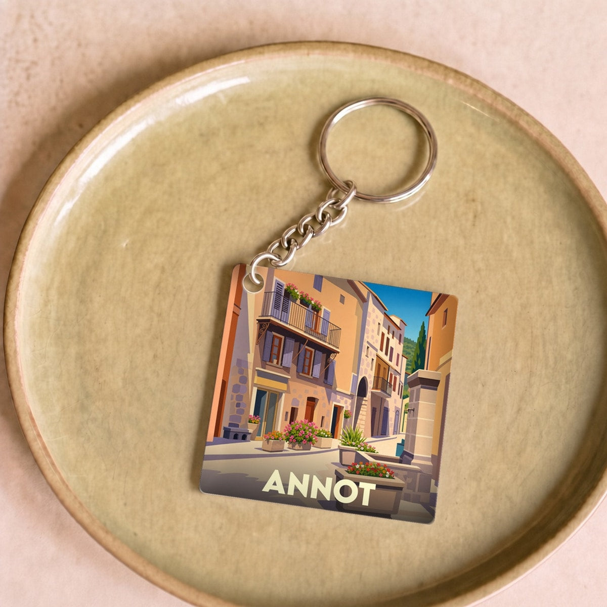 Porte-clés souvenir de la ville d'Annot avec une illustration stylisée d'une ruelle ensoleillée.