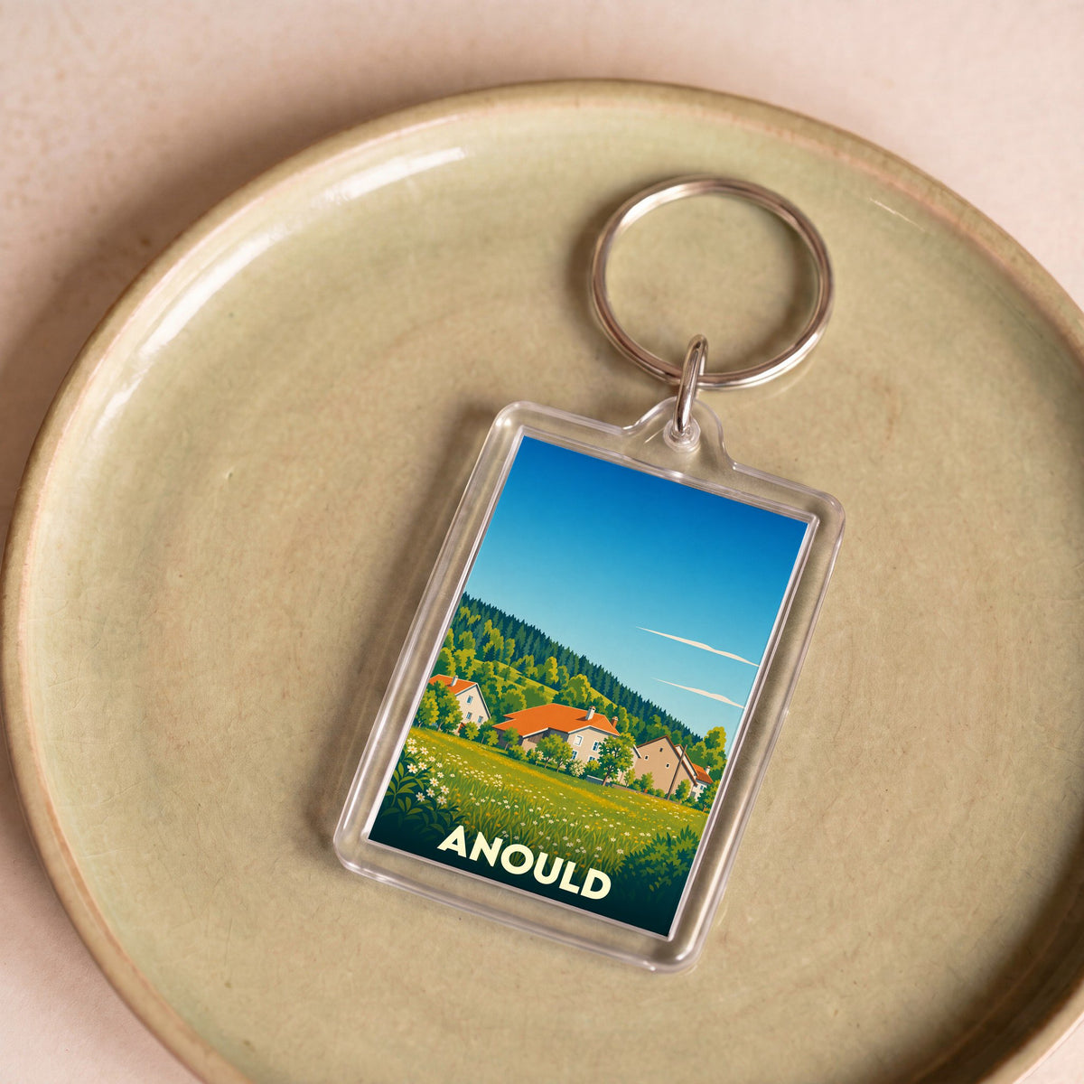 Porte-clés souvenir de la ville d'Anould avec une illustration paysagère stylisée.