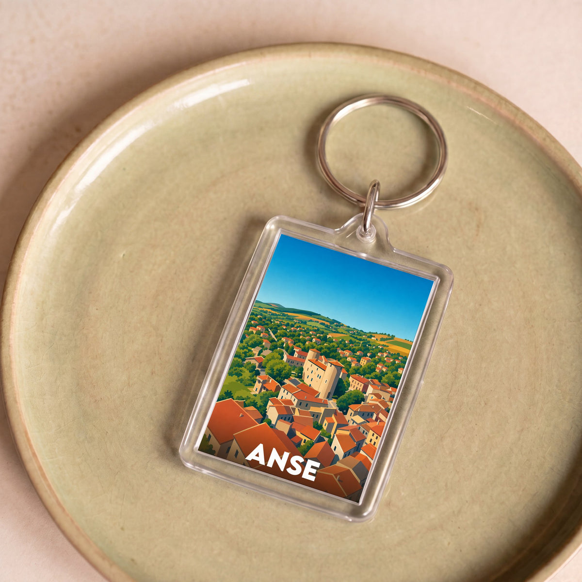 Porte-clés souvenir de la ville d'Anse avec une illustration stylisée de ses paysages et toitures.