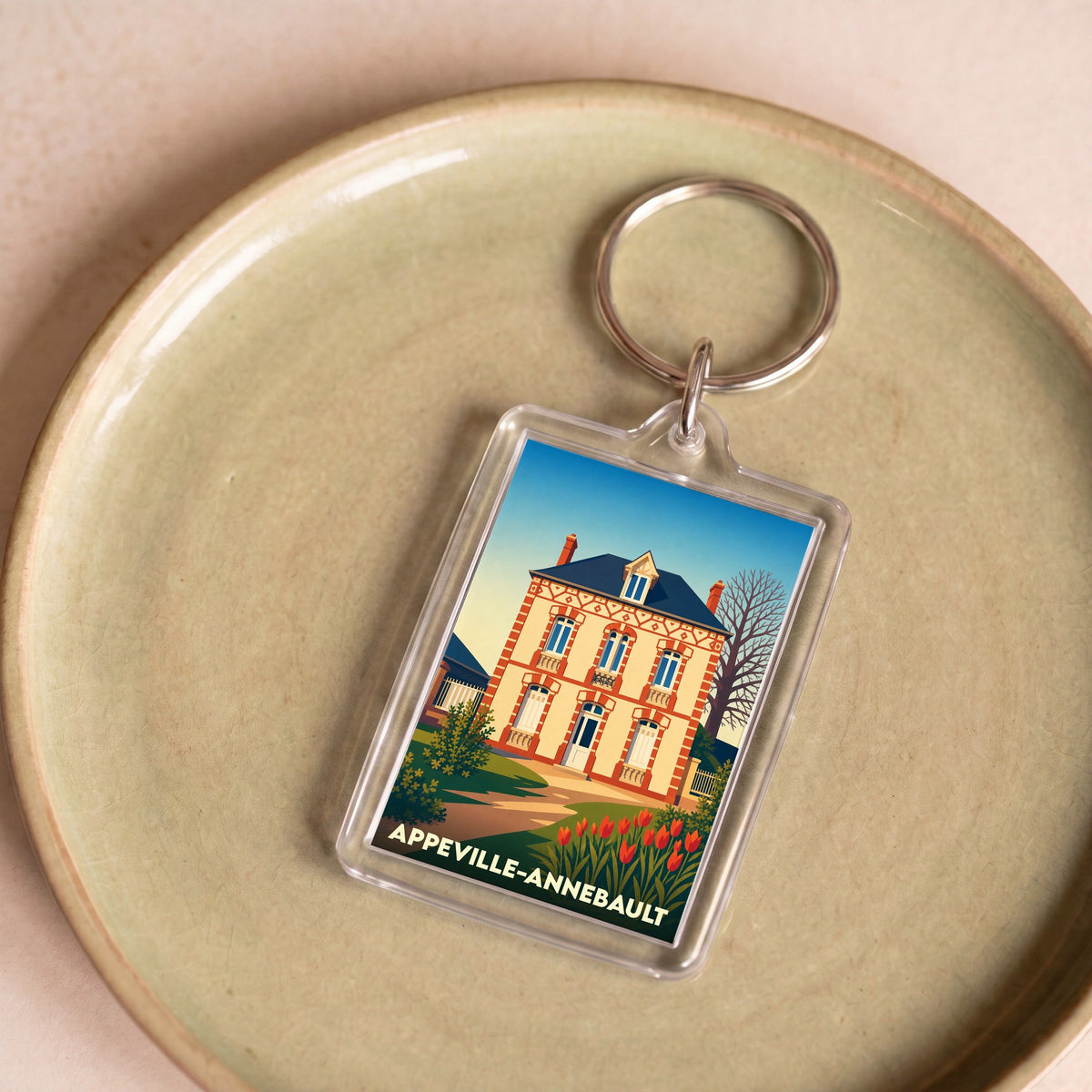 Porte-clés souvenir de la ville de Appeville-Annebault avec une illustration stylisée d'une maison traditionnelle.