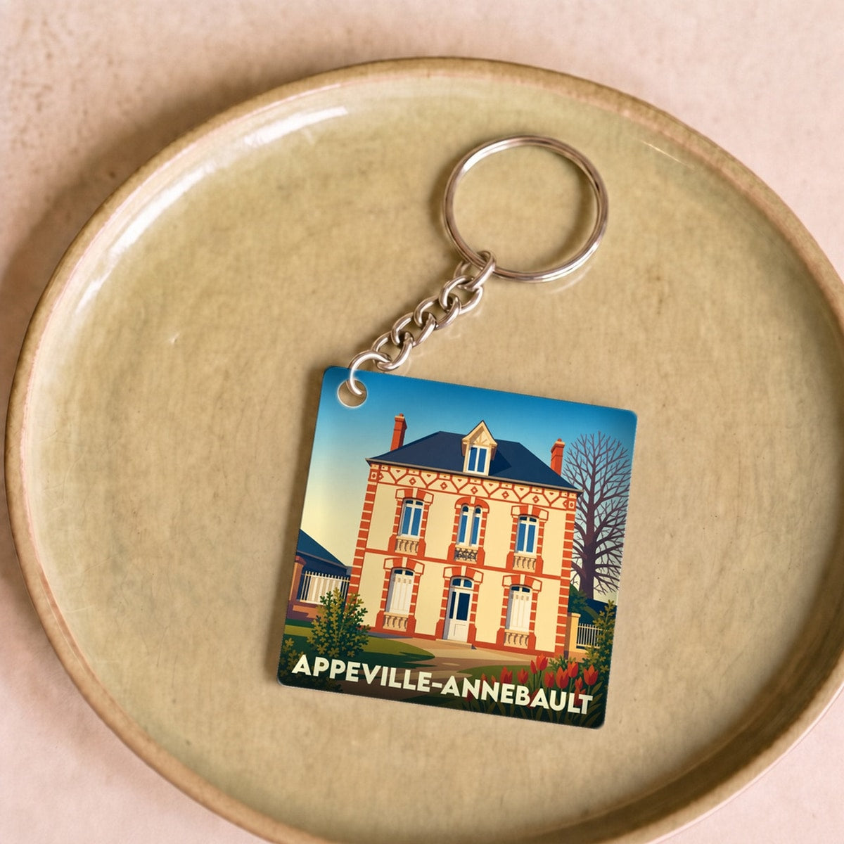 Porte-clés souvenir de la ville d'Appeville-Annebault avec une illustration stylisée d'une maison traditionnelle.