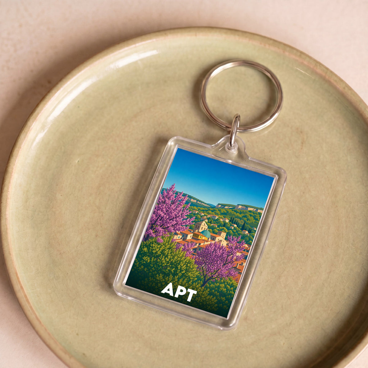 Porte-clés souvenir de la ville de Apt avec une illustration stylisée et colorée.