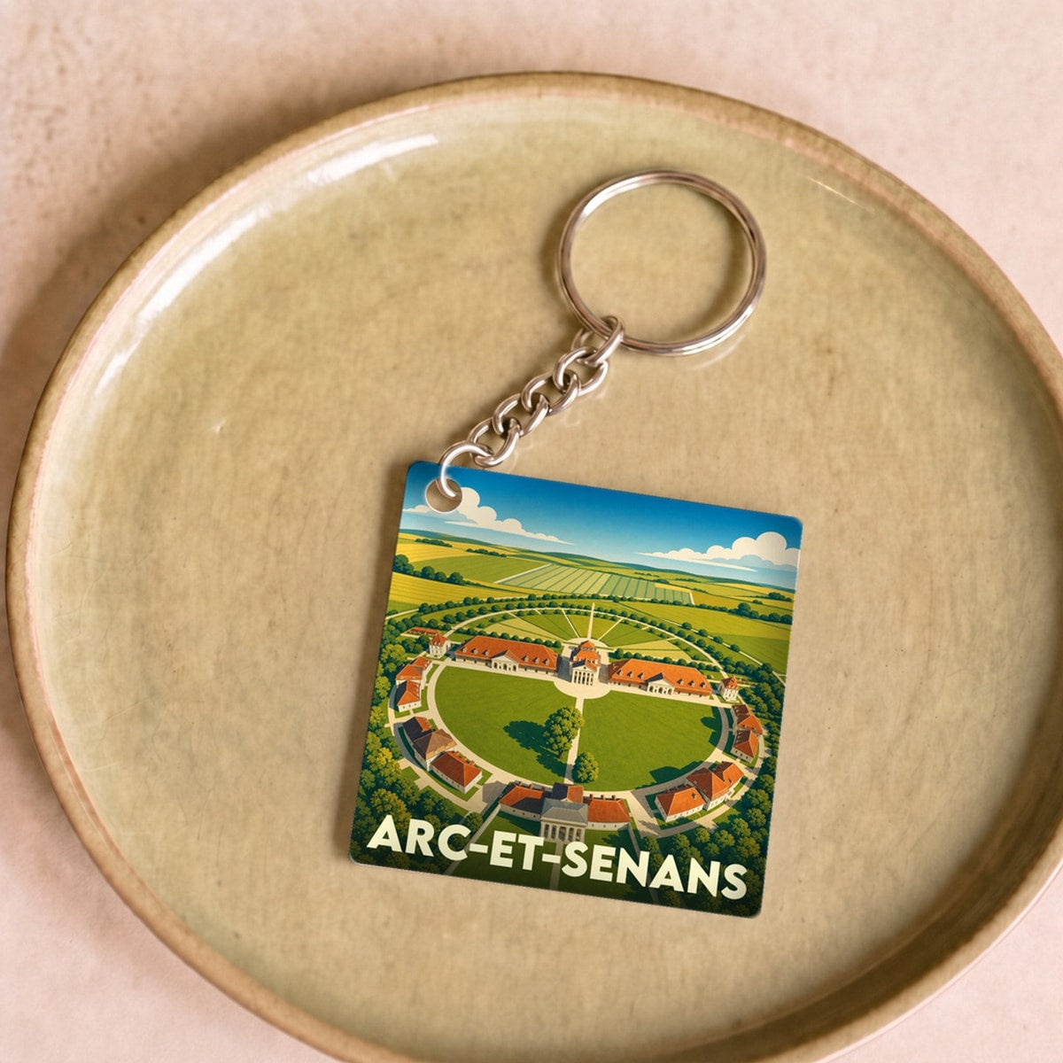 Porte-clés souvenir de la ville d’Arc-et-Senans illustrant la Saline royale avec un graphisme épuré.