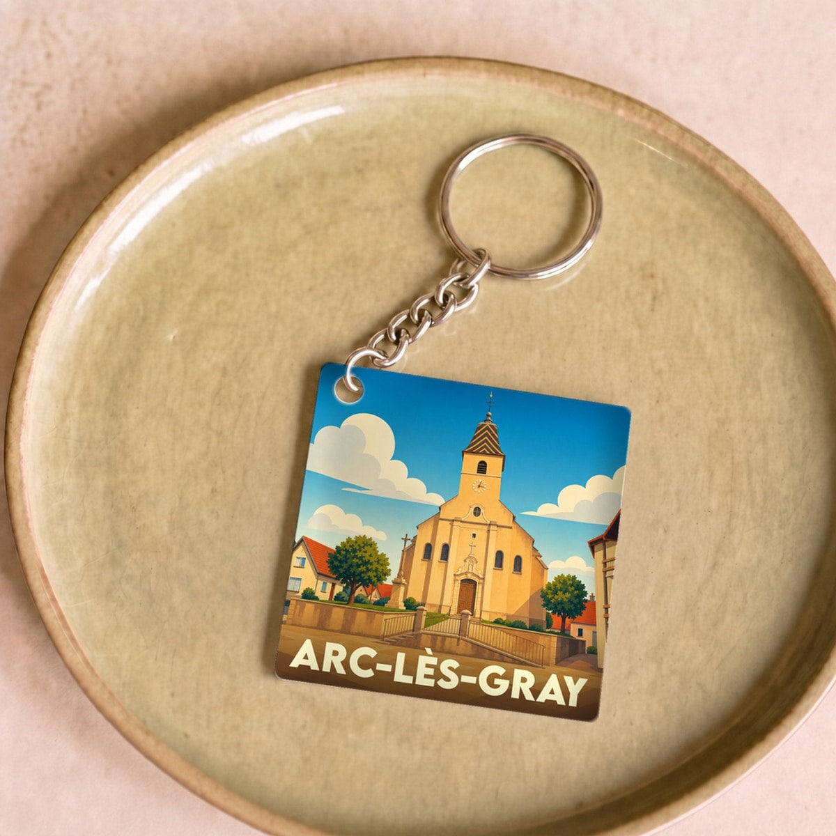 Porte-clés souvenir de la ville d'Arc-lès-Gray avec une illustration stylisée de son église.