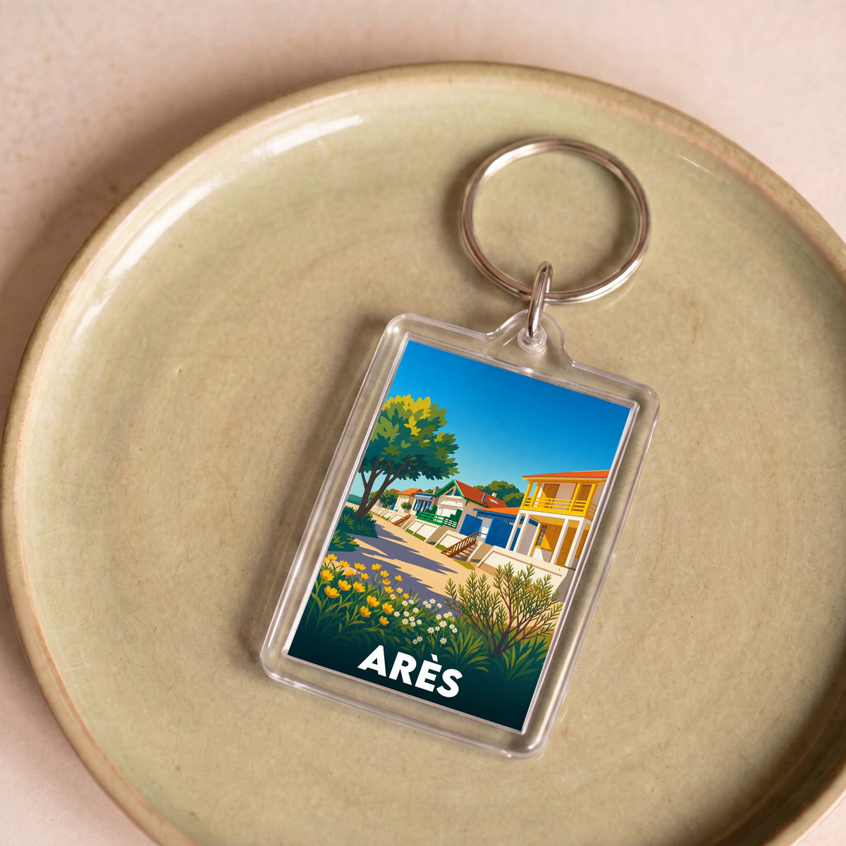 Porte-clés souvenir de la ville d'Arès avec une illustration stylisée de maisons colorées en bord de mer.
