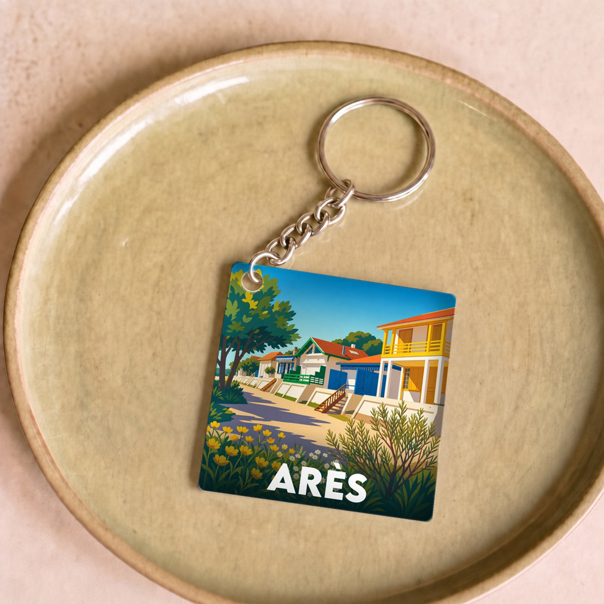 Porte-clés souvenir de la ville d'Arès avec une illustration stylisée de maisons colorées en bord de mer.