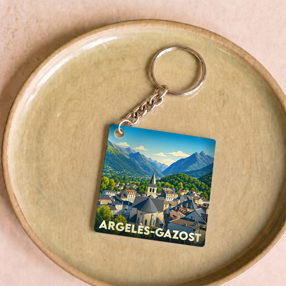Porte-clés souvenir de la ville d'Argelès-Gazost avec une illustration stylisée de ses montagnes et de son église.