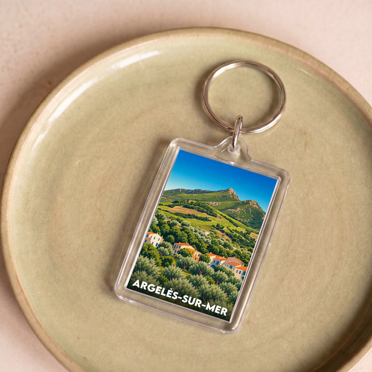 Porte-clés souvenir de la ville d'Argelès-sur-Mer avec une illustration de paysage côtier et montagneux.
