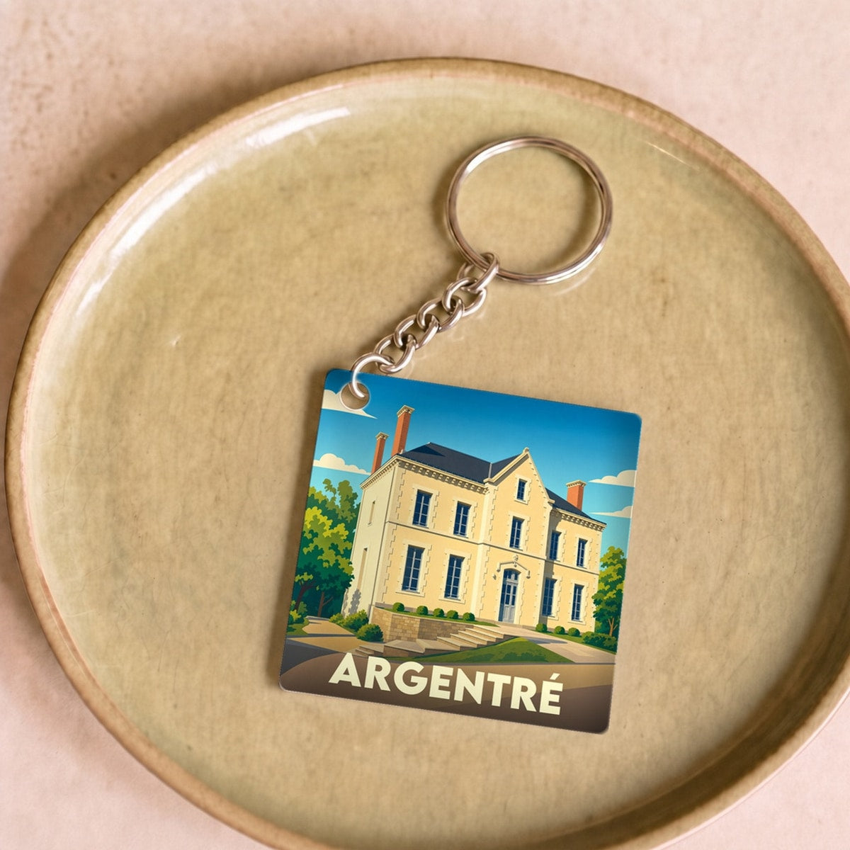 Porte-clés souvenir de la ville d'Argentré avec une illustration stylisée d'un manoir.