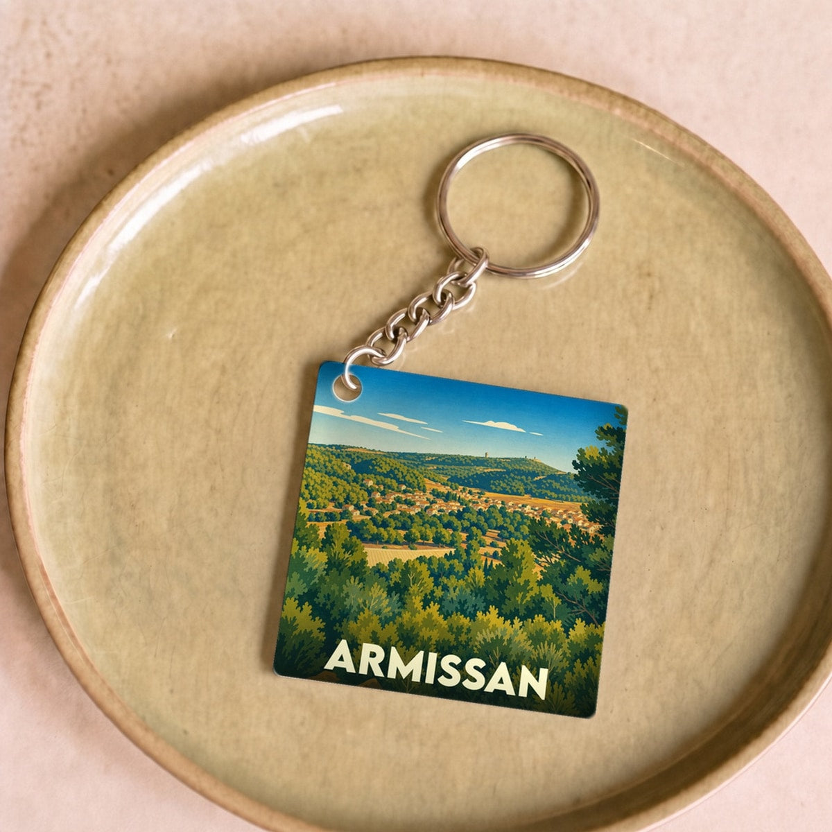Porte-clés souvenir de la ville d'Armissan avec une illustration stylisée d'un paysage vallonné.
