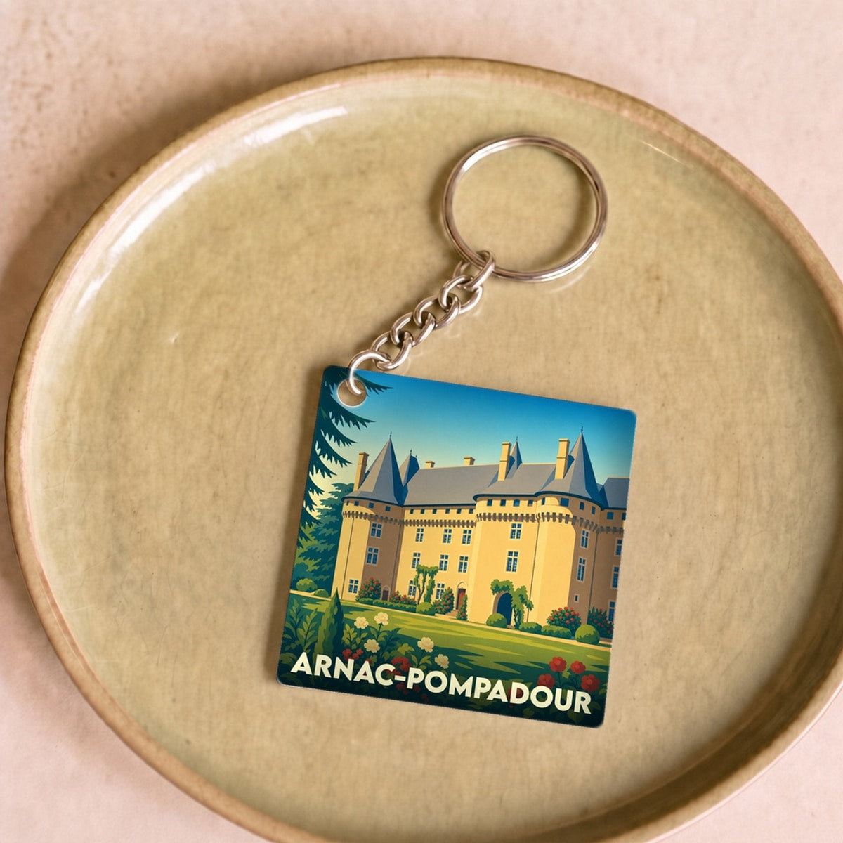 Porte-clés souvenir de la ville d'Arnac-Pompadour avec une illustration stylisée de son château.