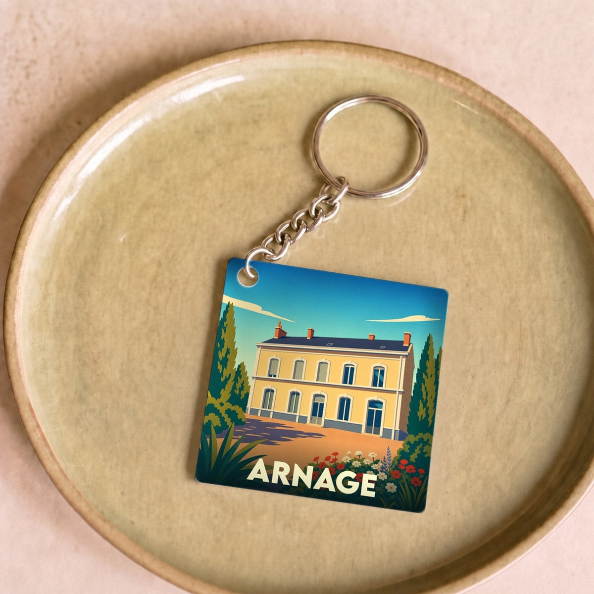 Porte-clés souvenir de la ville de Arnage avec une illustration stylisée d'une bâtisse colorée.