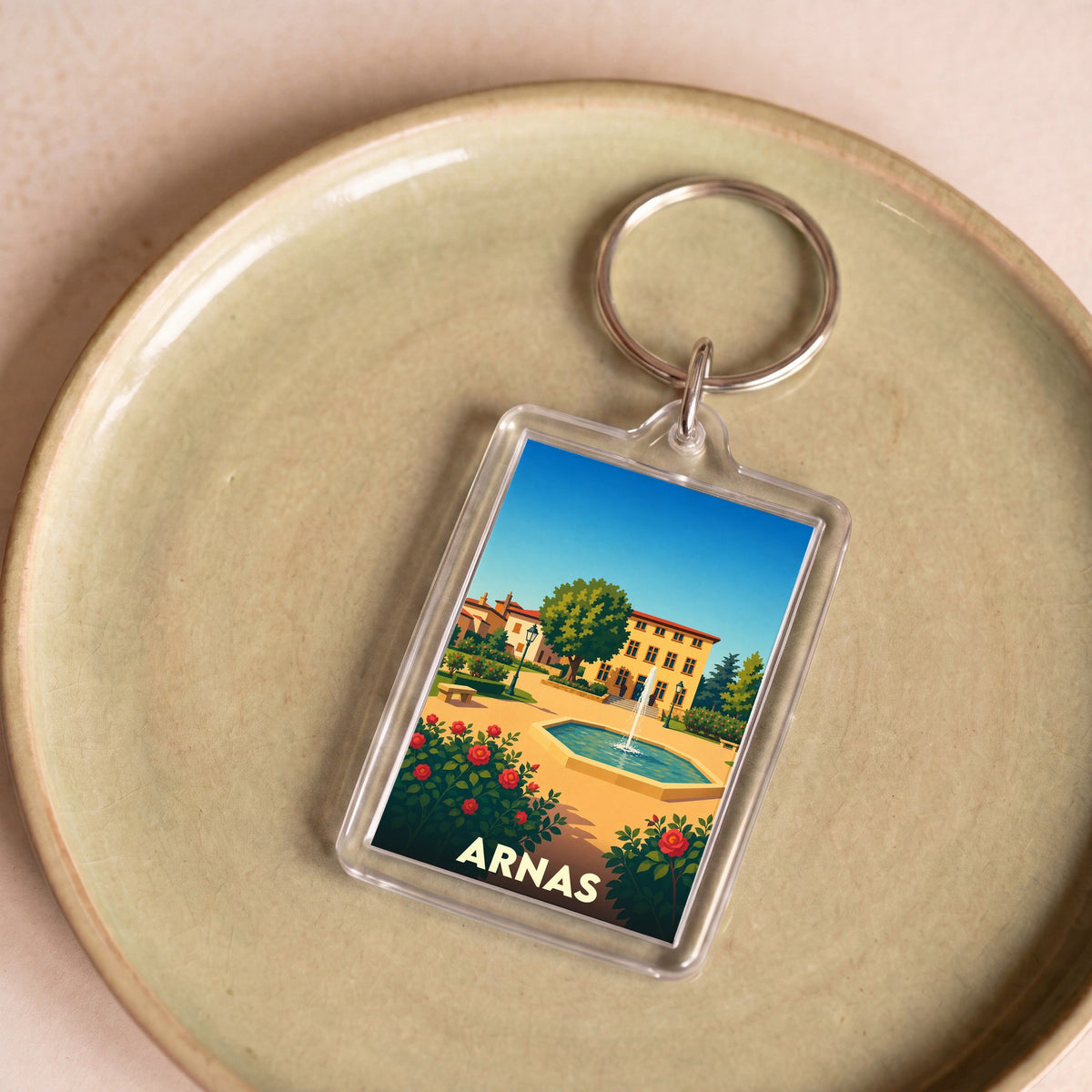 Porte-clés souvenir de la ville d'Arnas avec une illustration stylisée d'un parc ensoleillé.