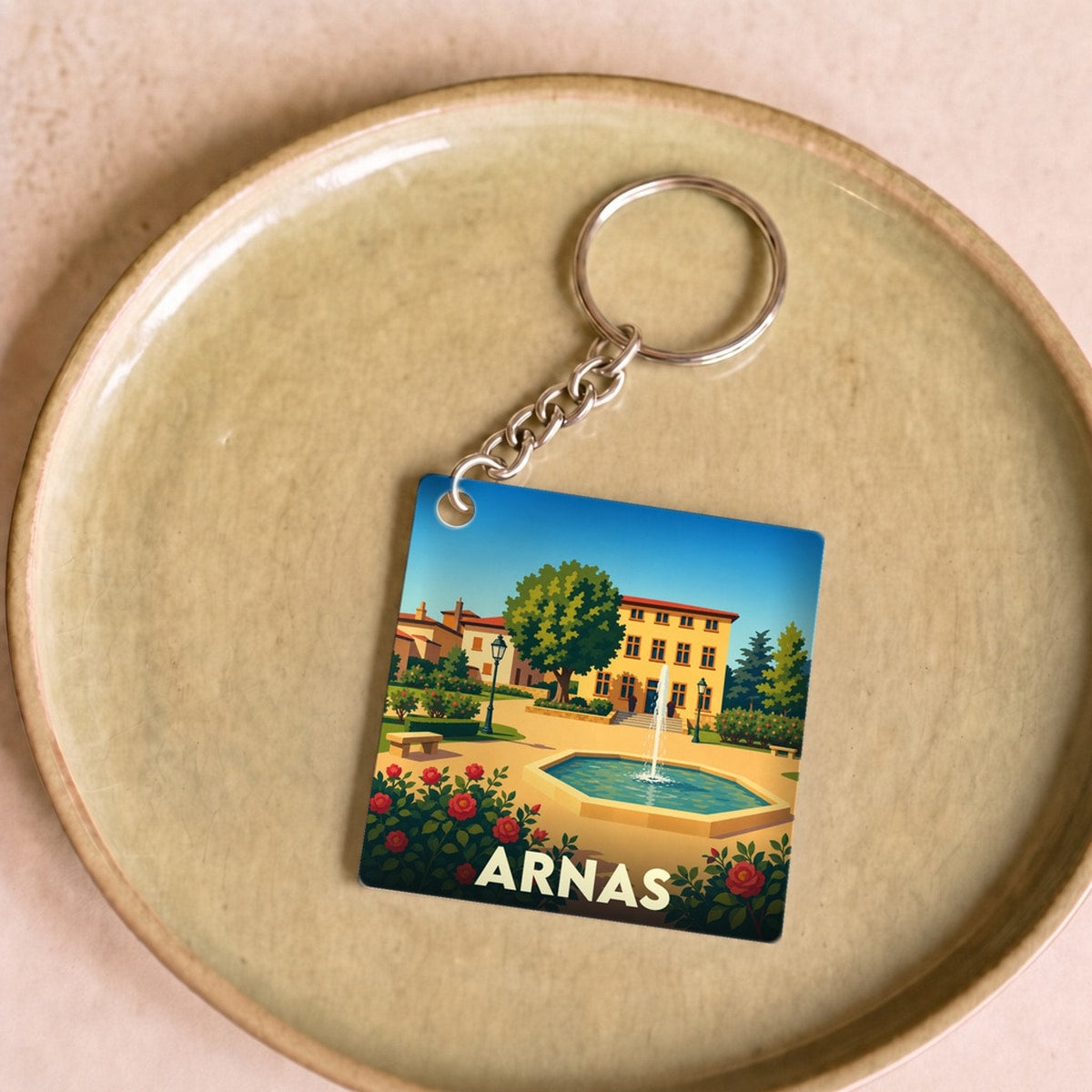 Porte-clés souvenir de la ville d'Arnas avec une illustration stylisée d'un parc ensoleillé.