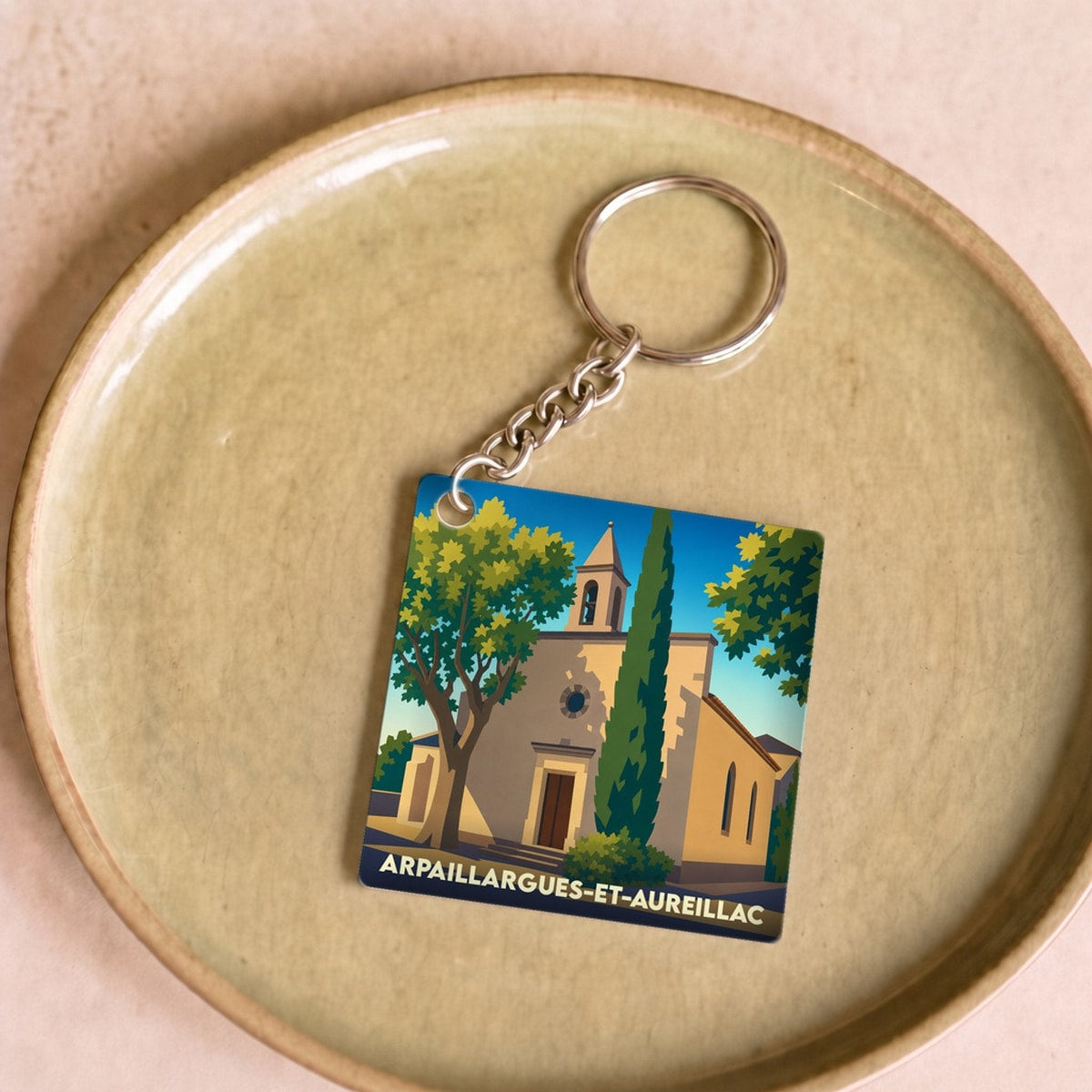 Porte-clés souvenir de la ville de Arpaillargues-et-Aureillac avec une illustration stylisée de son église.