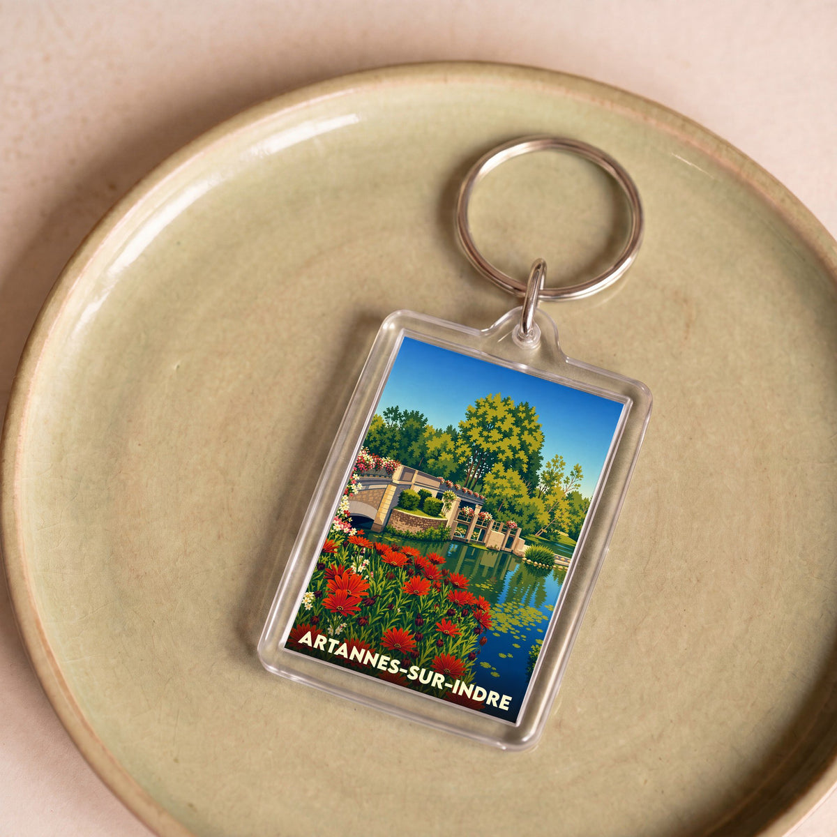 Porte-clés souvenir de la ville d'Artannes-sur-Indre avec une illustration stylisée d'un pont fleuri.