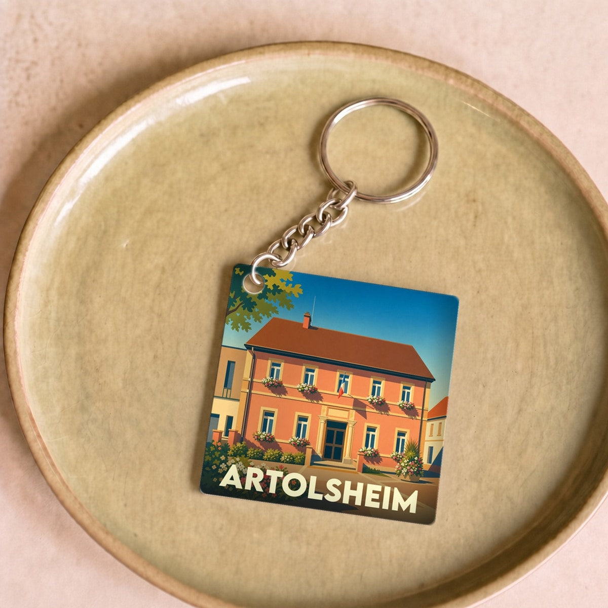 Porte-clés souvenir de la ville de Artolsheim avec une illustration stylisée d'une maison fleurie.