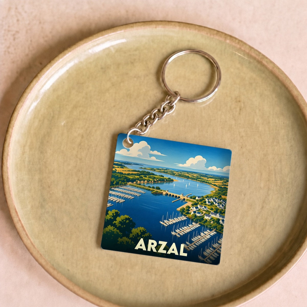 Porte-clés souvenir de la ville d'Arzal avec une illustration stylisée de son port et de son barrage.