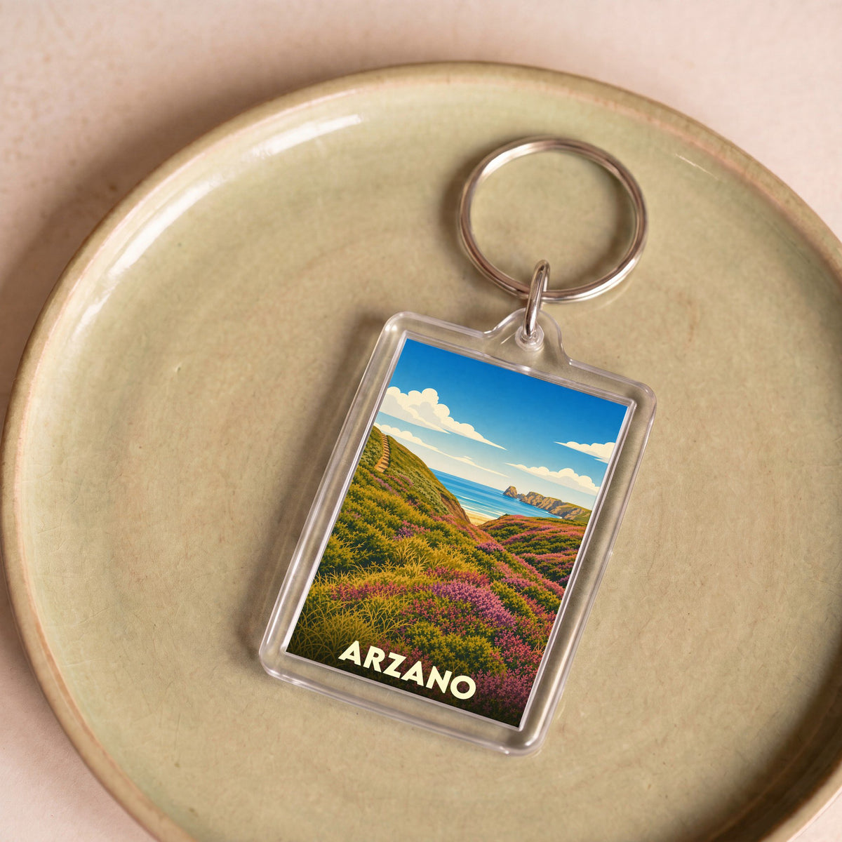 Porte-clés souvenir de la ville d'Arzano avec une illustration stylisée de paysage côtier.