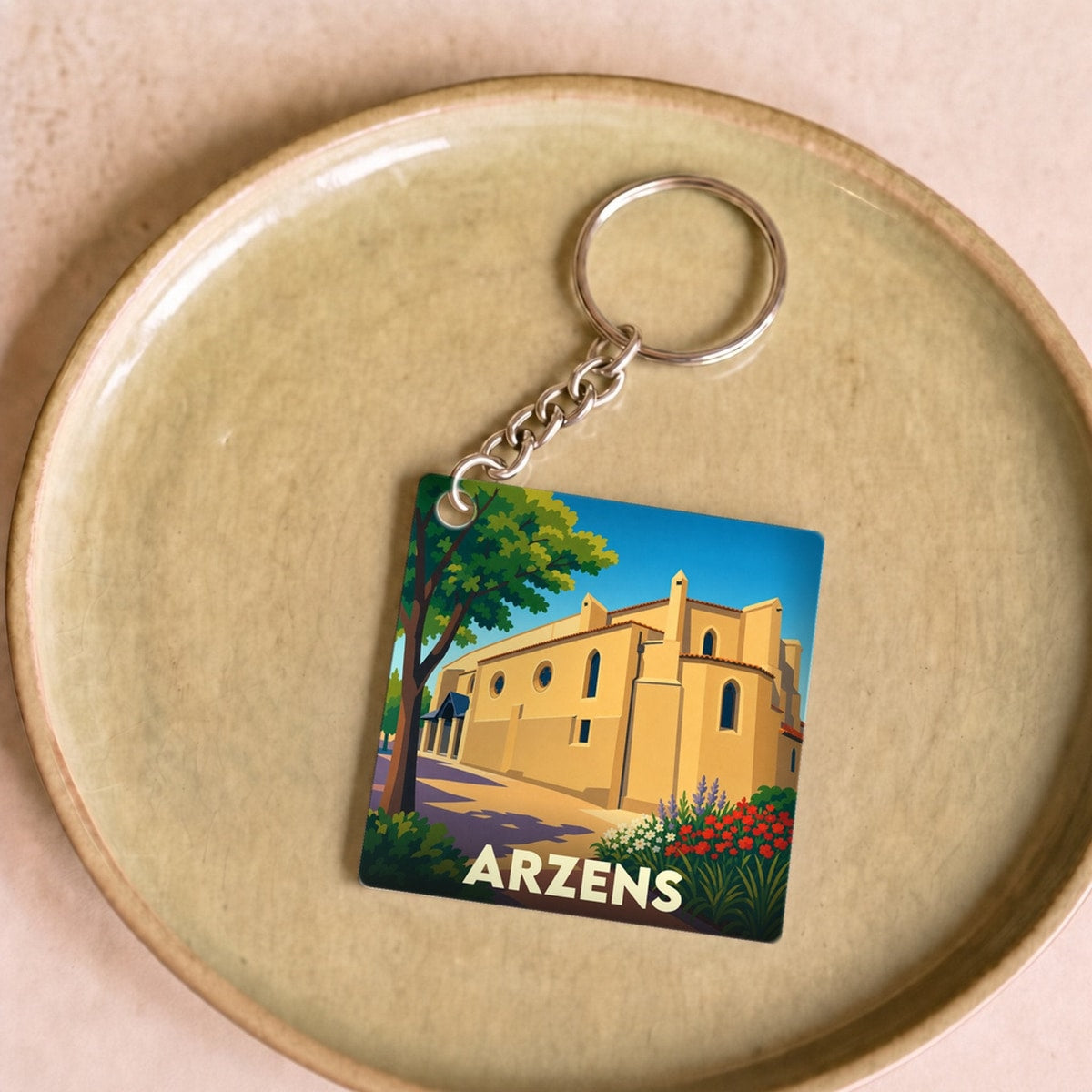 Porte-clés souvenir de la ville d'Arzens avec une illustration stylisée de son église.