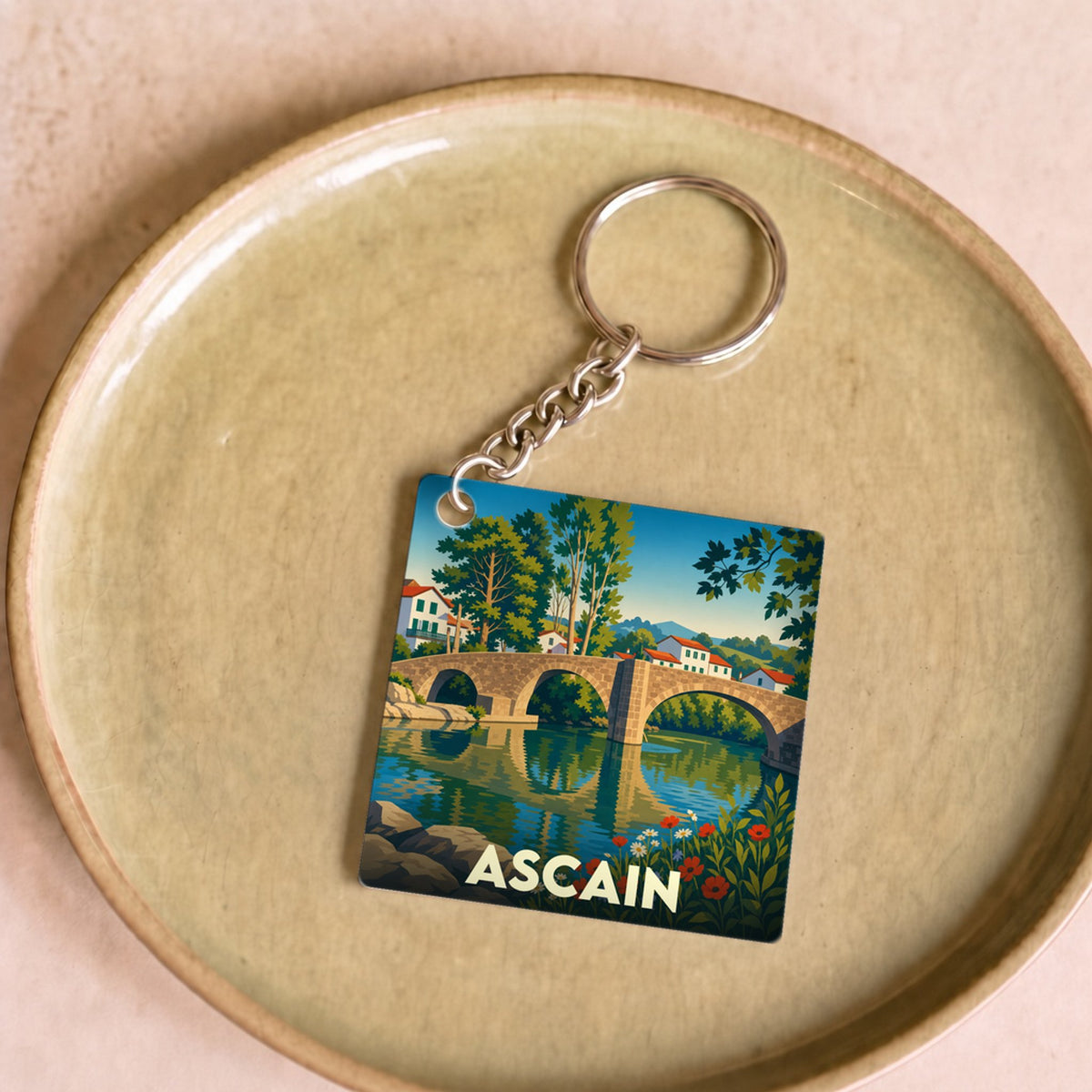 Porte-clés souvenir de la ville d'Ascain avec une illustration stylisée de son pont romain.