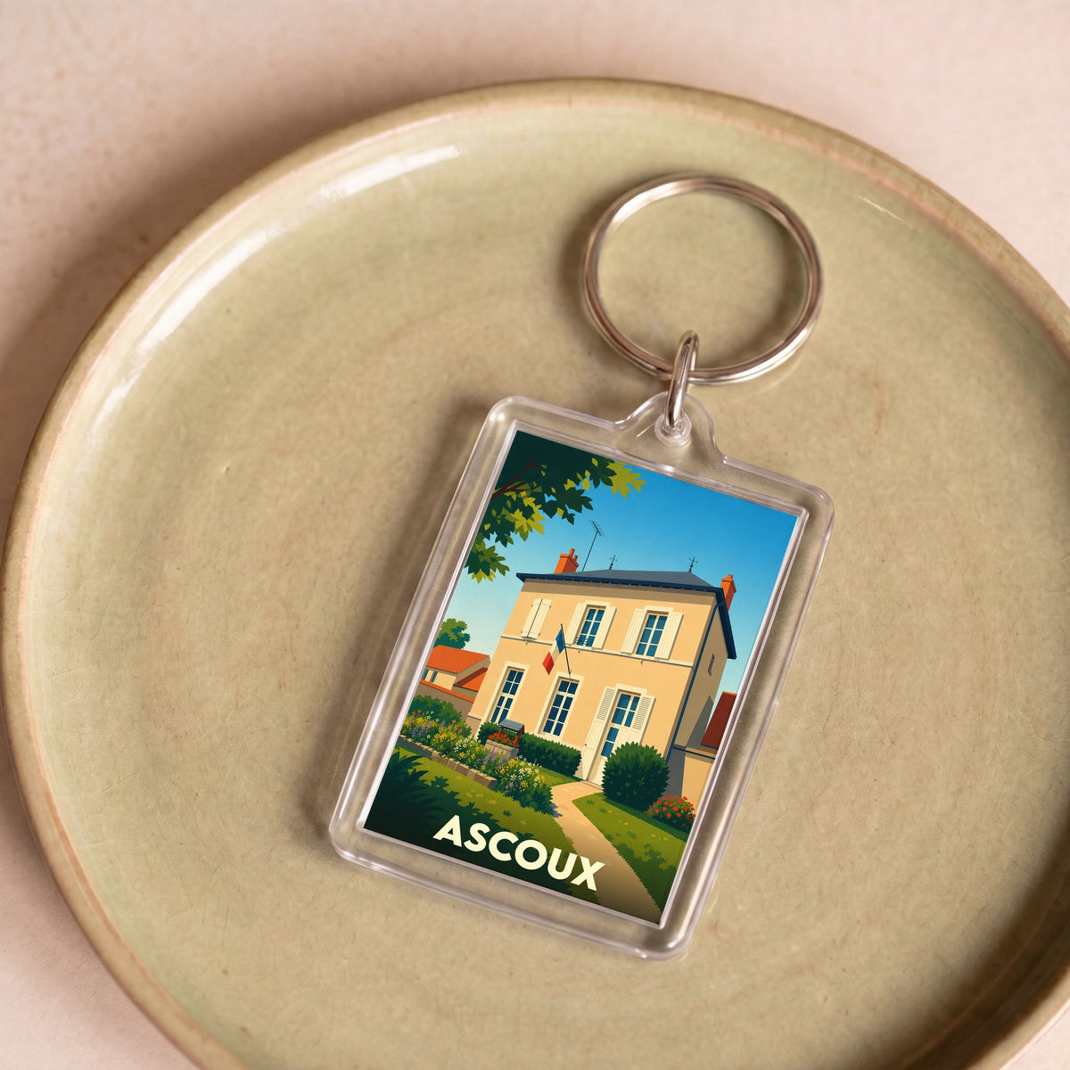 Porte-clés souvenir de la ville d'Ascoux avec une illustration stylisée de sa mairie.