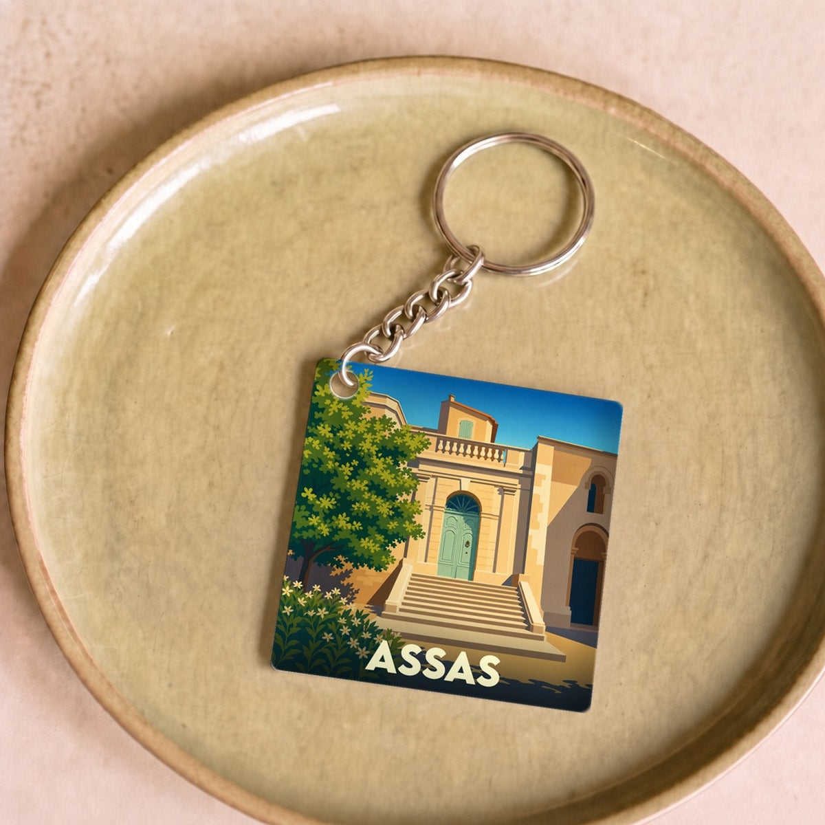Porte-clés souvenir de la ville d'Assas avec une illustration stylisée de son patrimoine.