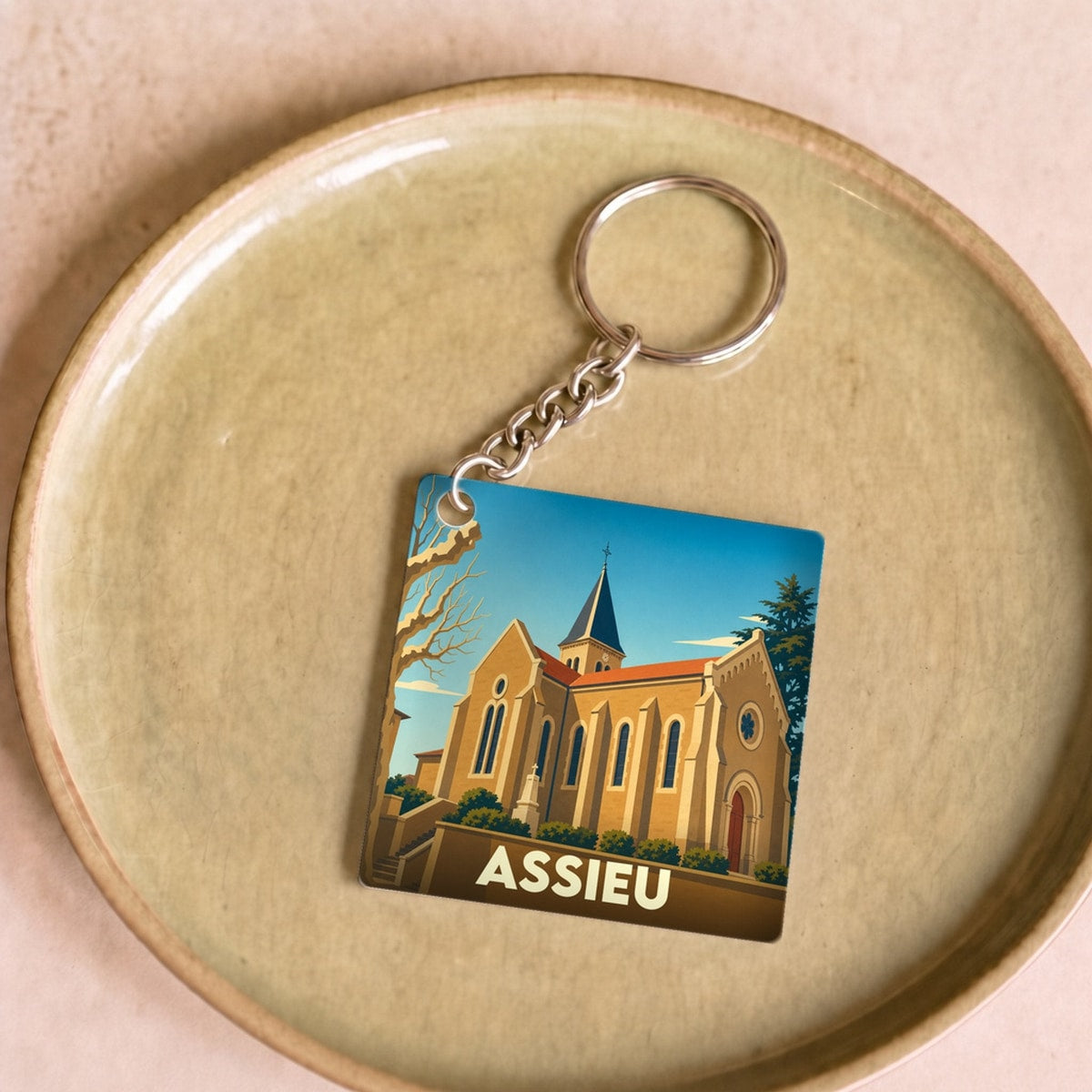 Porte-clés souvenir de la ville d'Assieu avec une illustration stylisée de son église.