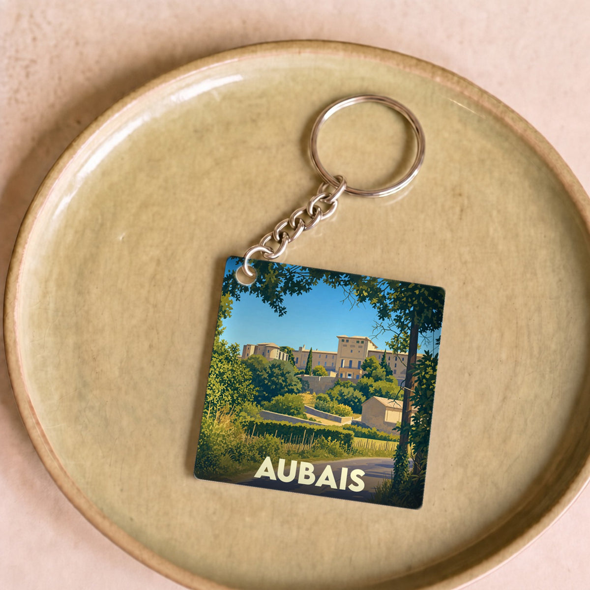 Porte-clés souvenir de la ville d'Aubais avec une illustration stylisée de son paysage.