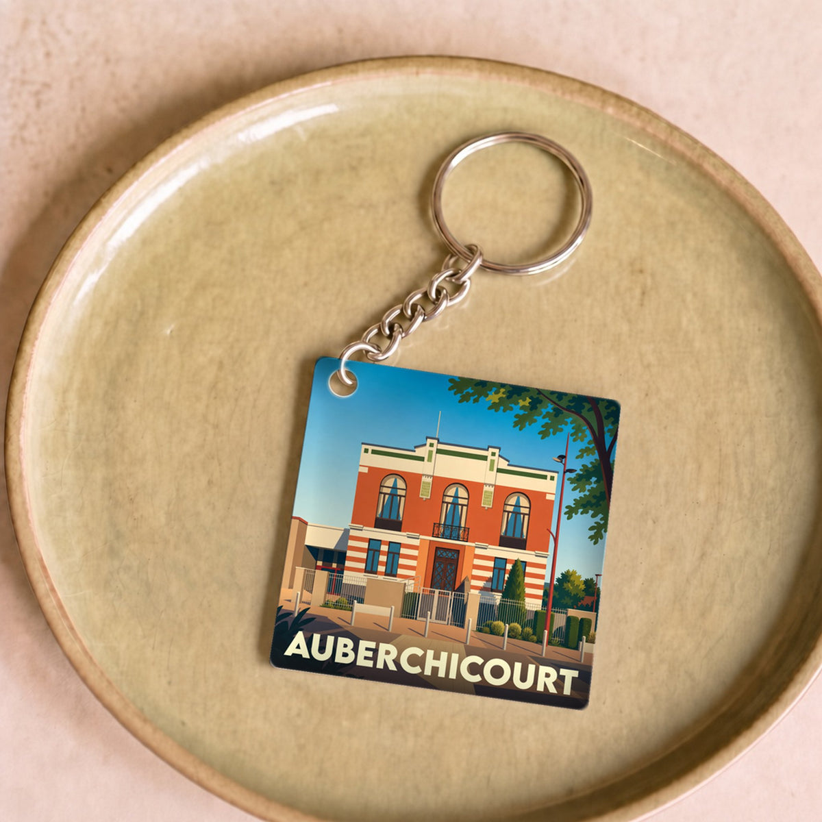 Porte-clés souvenir de la ville d'Auberchicourt avec une illustration stylisée d'un bâtiment remarquable.
