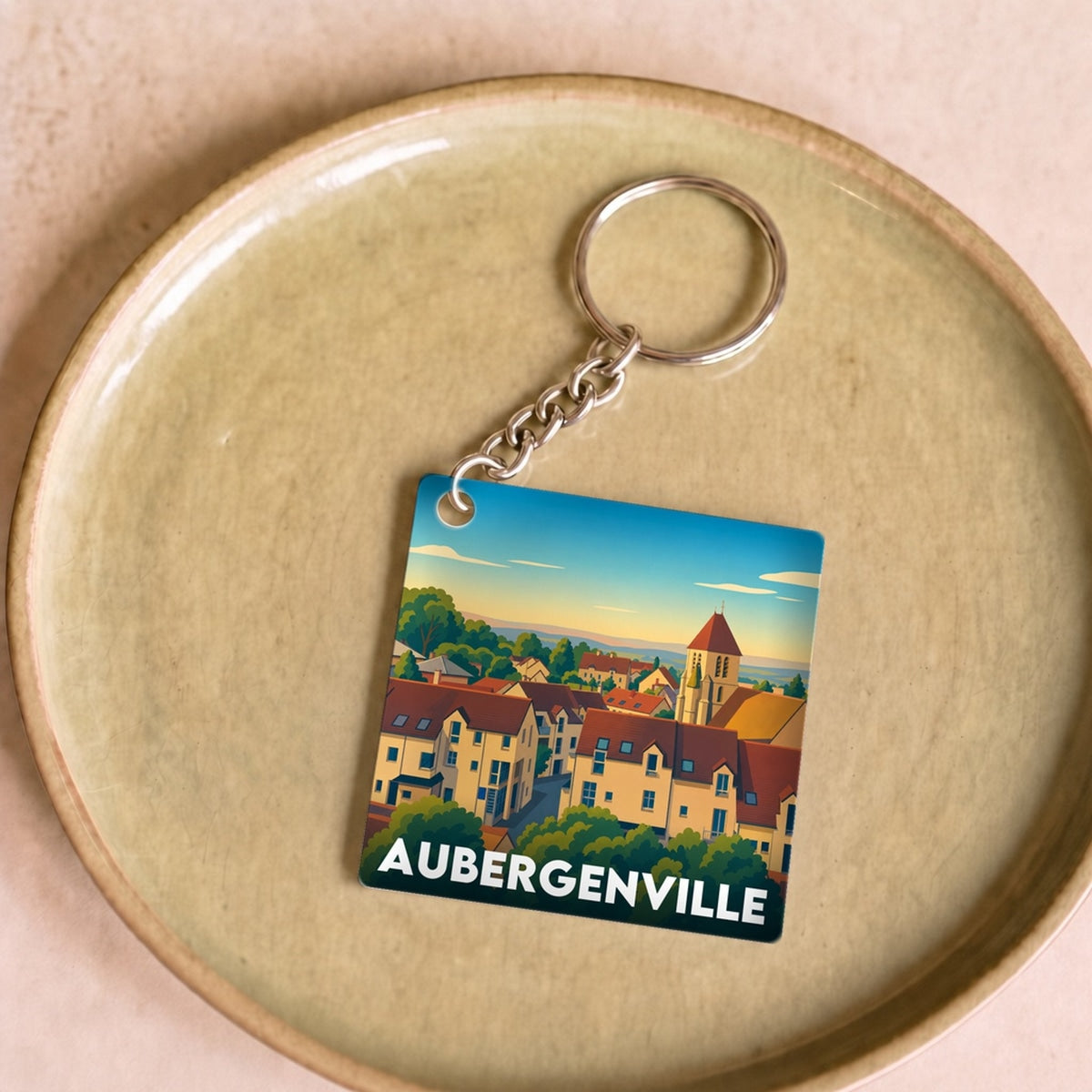 Porte-clés souvenir de la ville d'Aubergenville avec une illustration colorée et stylisée.