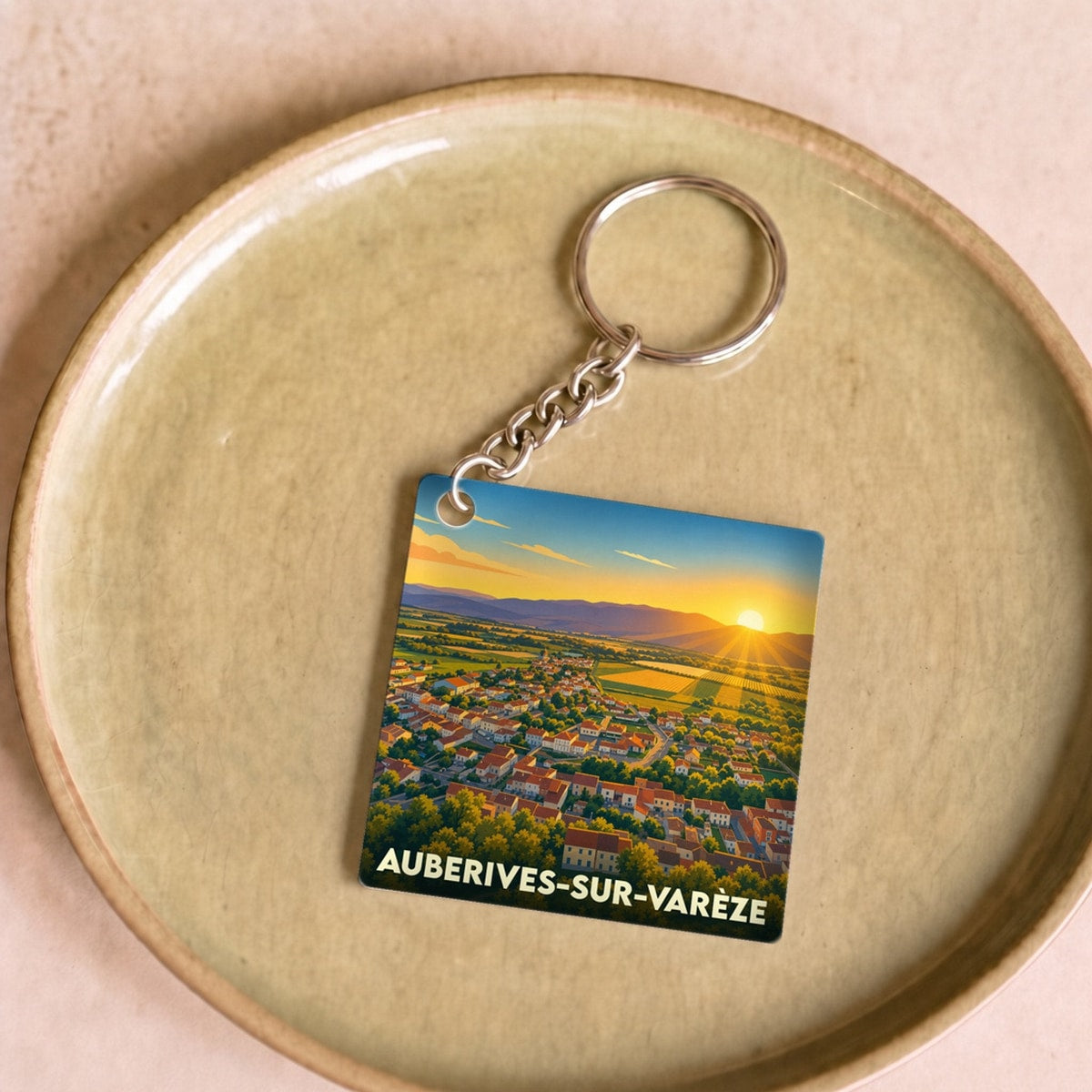 Porte-clés souvenir de la ville d'Auberives-sur-Varèze avec une illustration stylisée d'un coucher de soleil sur le village.