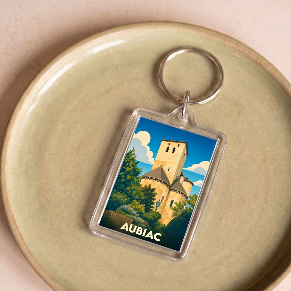 Porte-clés souvenir de la ville d'Aubiac avec une illustration stylisée de son église romane.